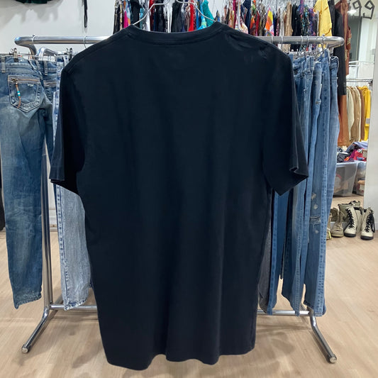 Black t-shirt on a hanger with jeans and other clothing in the background