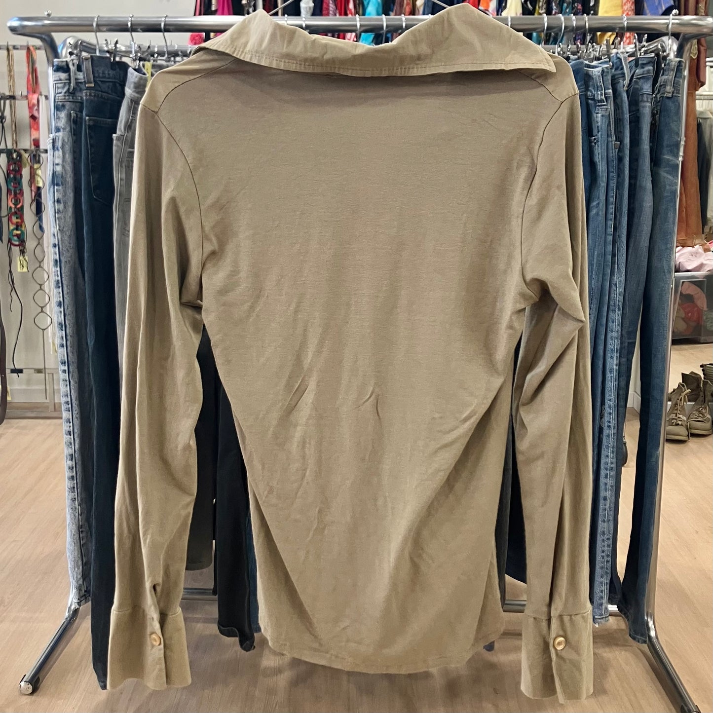 Beige shirt on a rack with jeans in a store setting