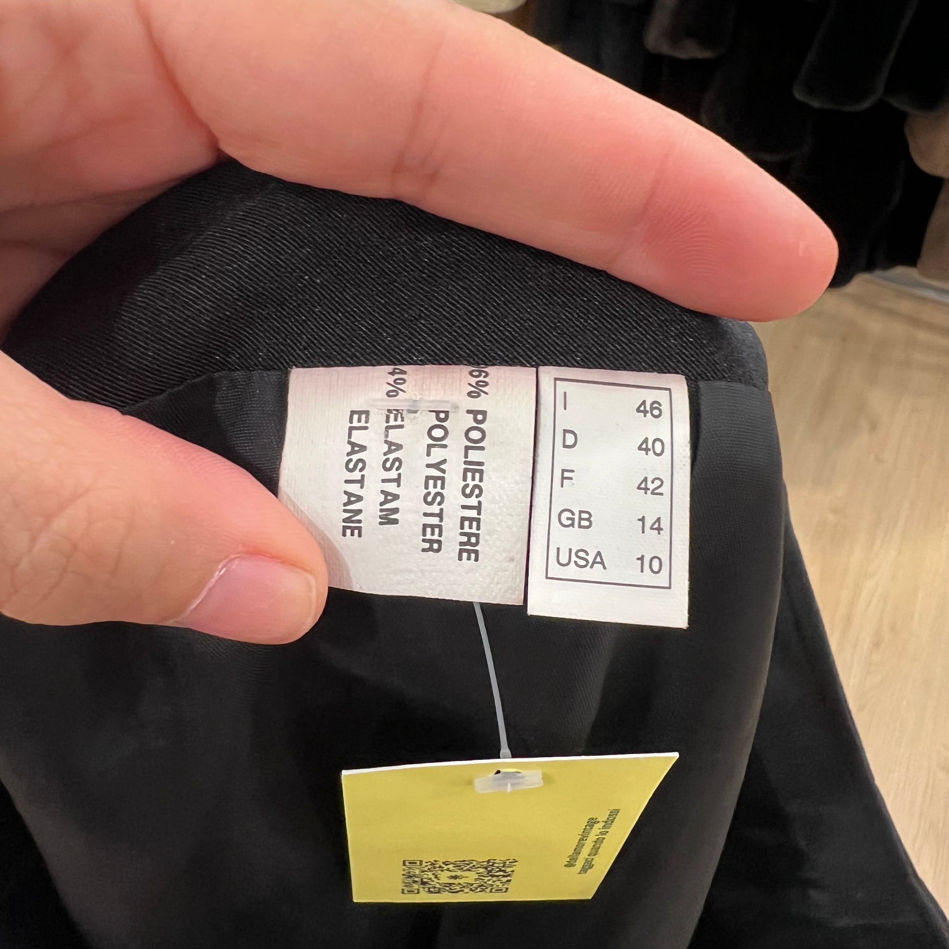Clothing label with size and material information on a black garment