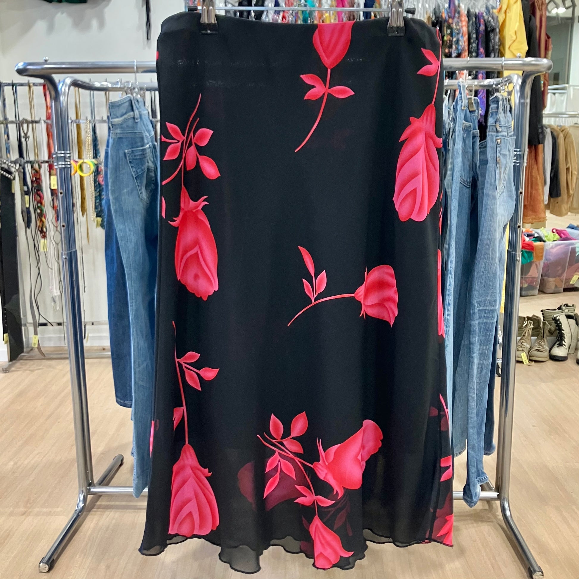 Black dress with pink floral patterns hanging on a rack in a store