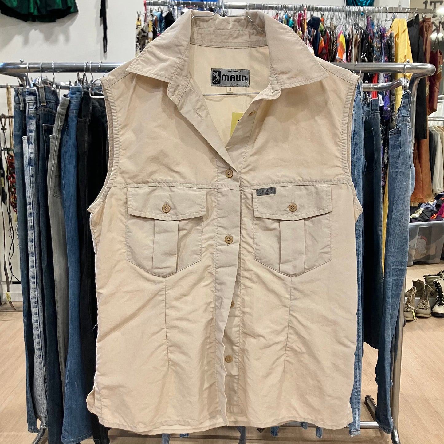 Beige vest on a rack with jeans in a clothing store