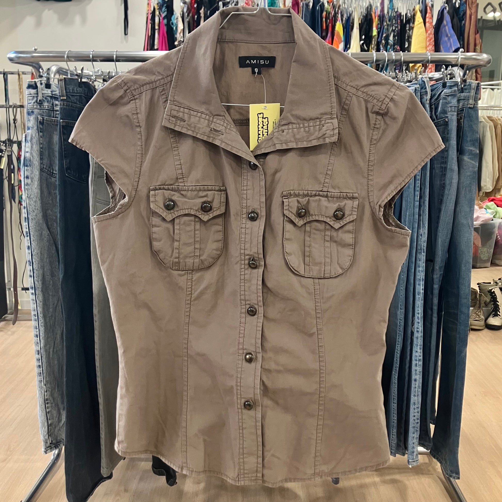 Beige sleeveless shirt with a brand tag on a rack in a store setting