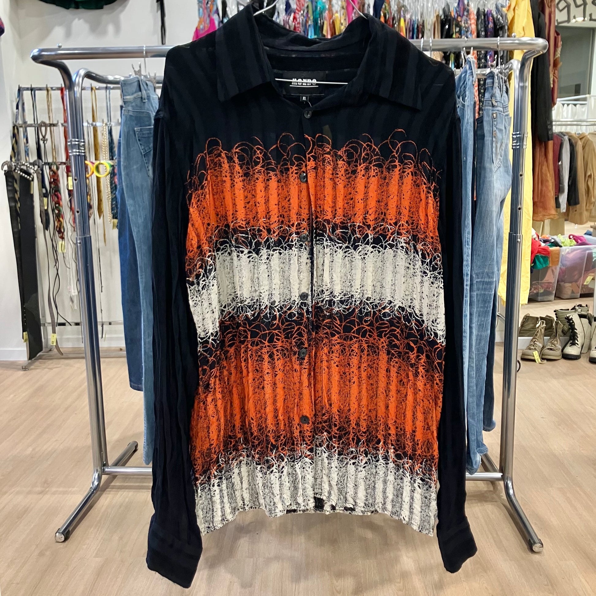 Black shirt with orange and white pattern on a clothing rack in a store