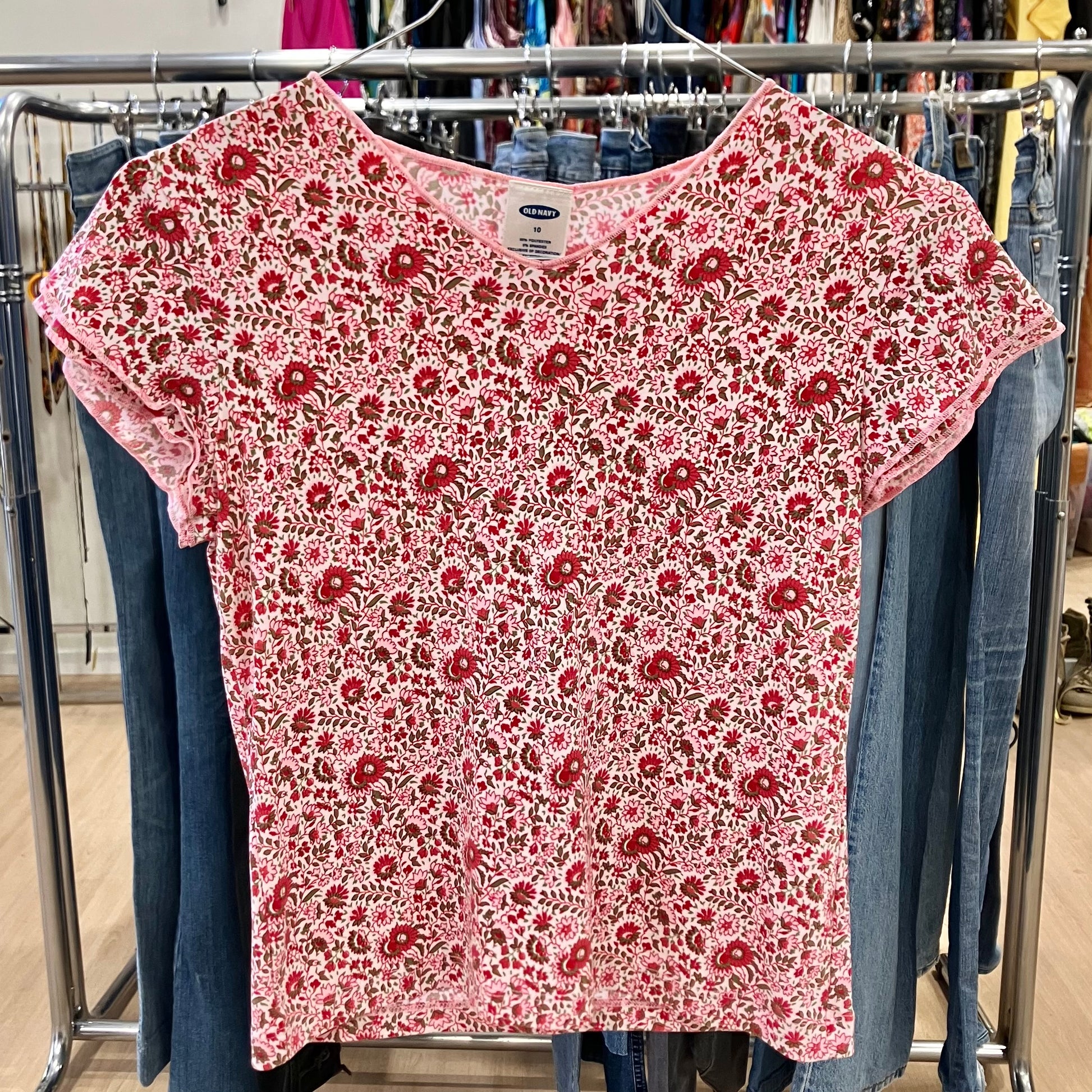 Red floral-patterned shirt on a clothing rack with jeans