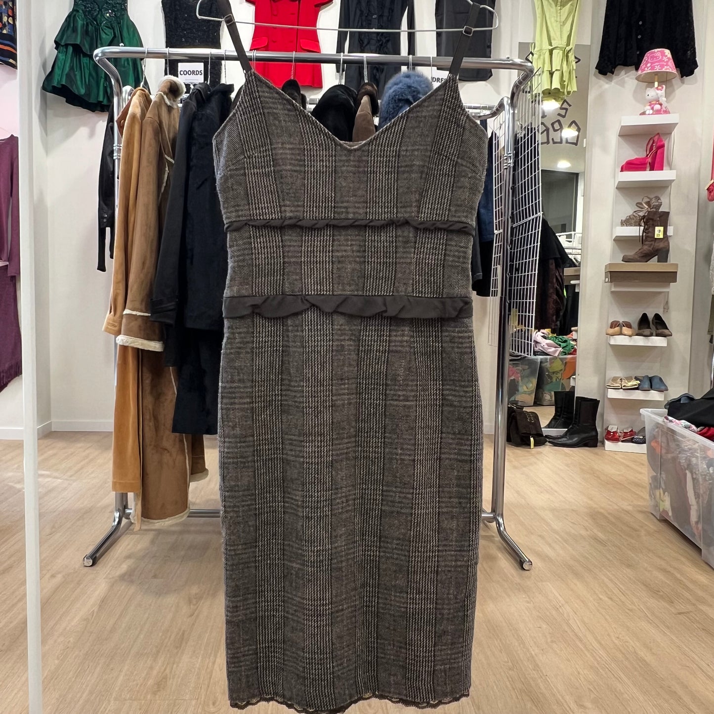 Gray checkered dress on a rack in a store setting with various clothing items in the background.