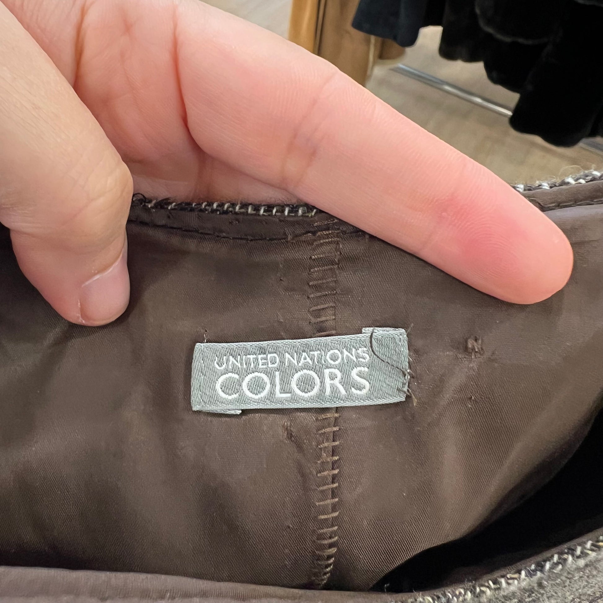 Hand holding a brown fabric with a 'United Nations Colors' label.