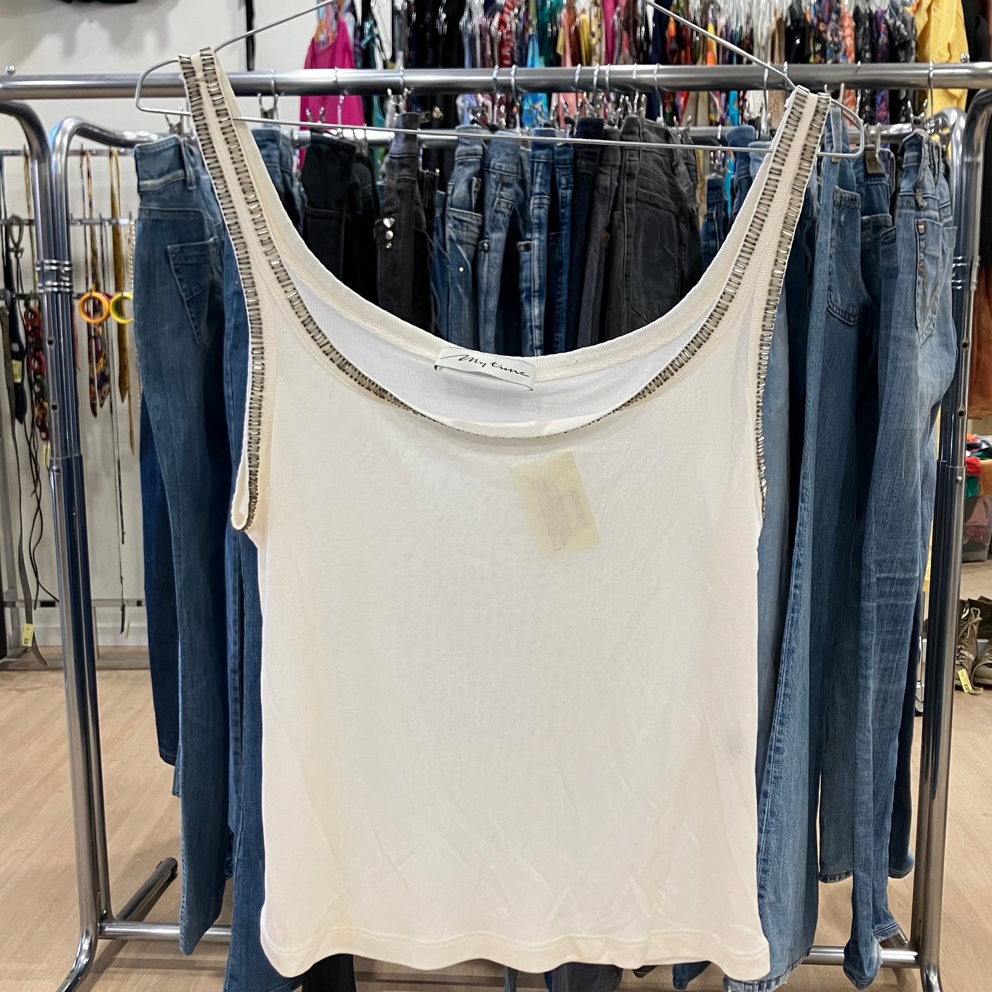 White tank top with a stain hanging on a rack with jeans