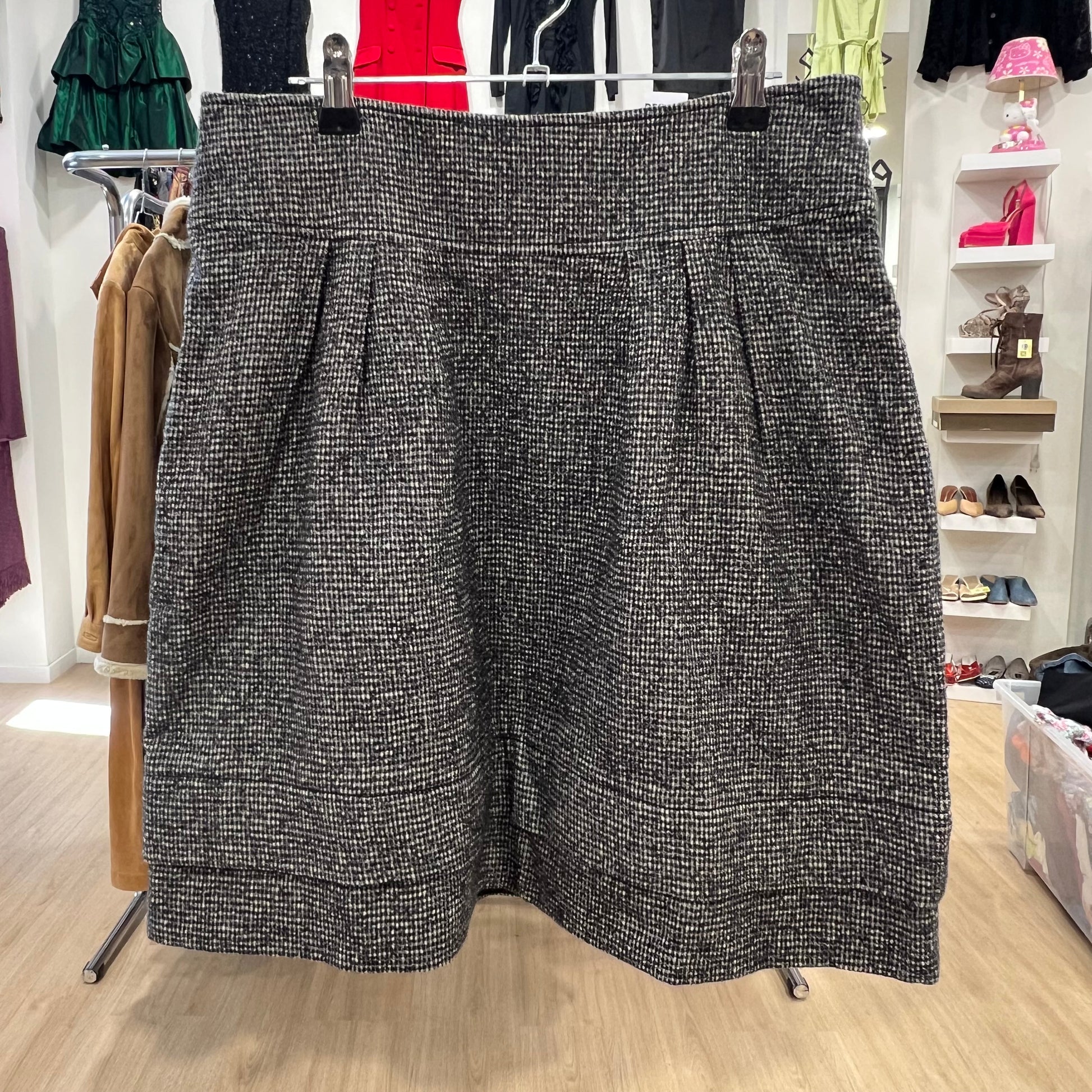 Black and white patterned skirt hanging on a rack in a store setting with shoes and clothing in the background