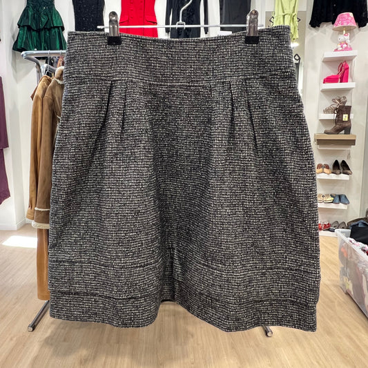 Black and white patterned skirt hanging on a rack in a store setting with shoes and clothing in the background