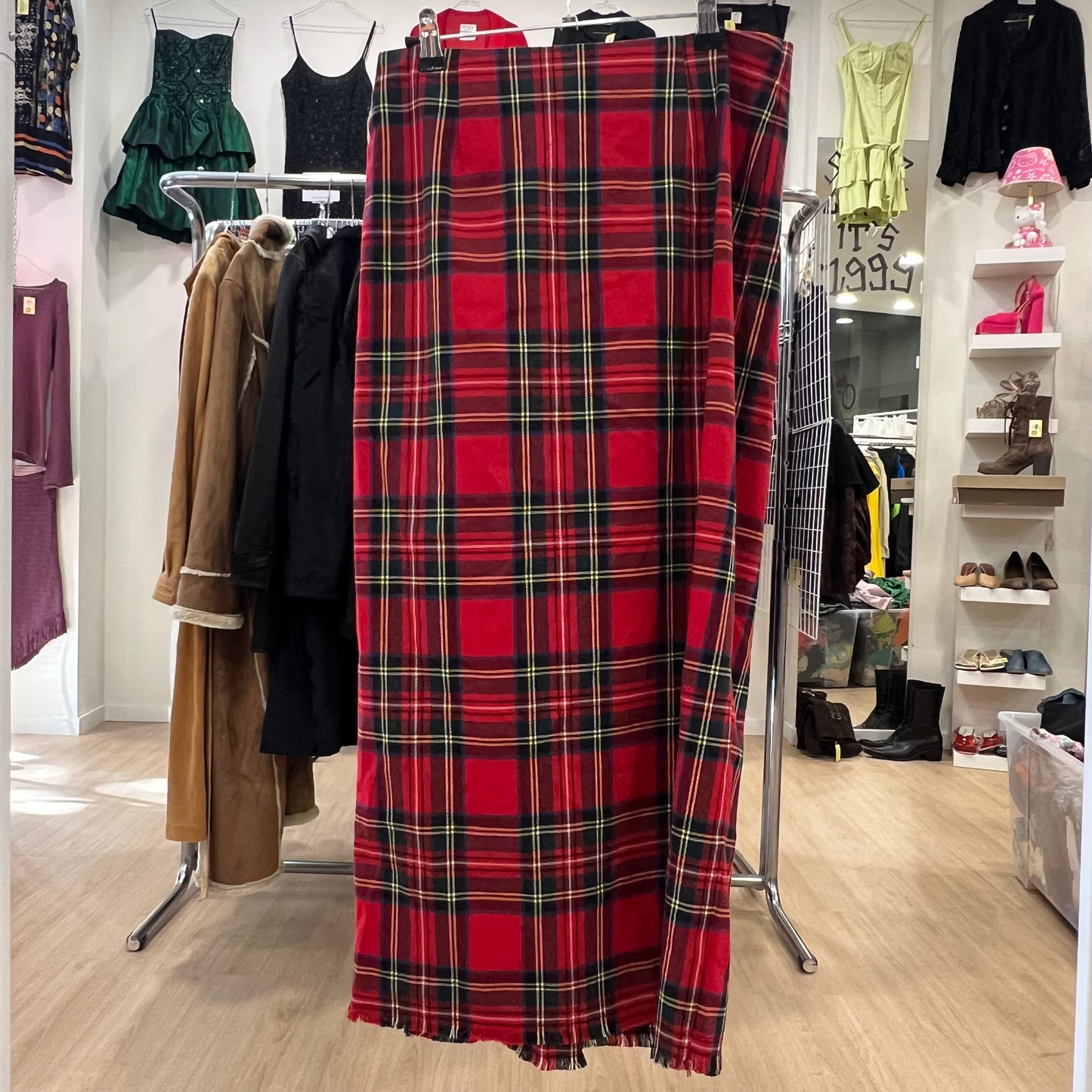 Red plaid skirt on a clothing rack in a store setting with various garments