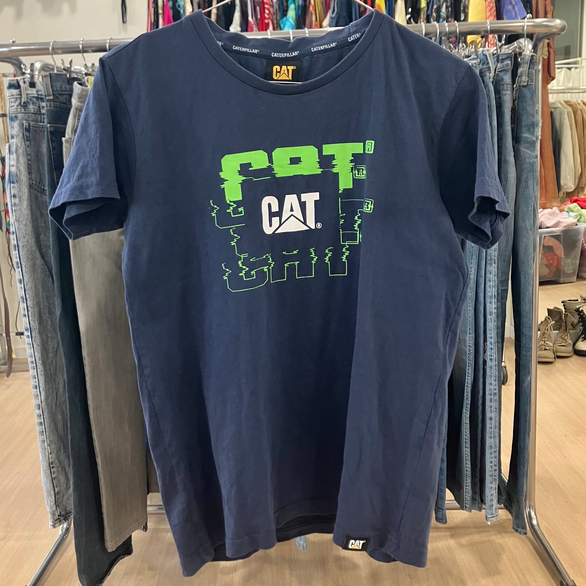 Navy blue t-shirt with green and white logo on a clothing rack