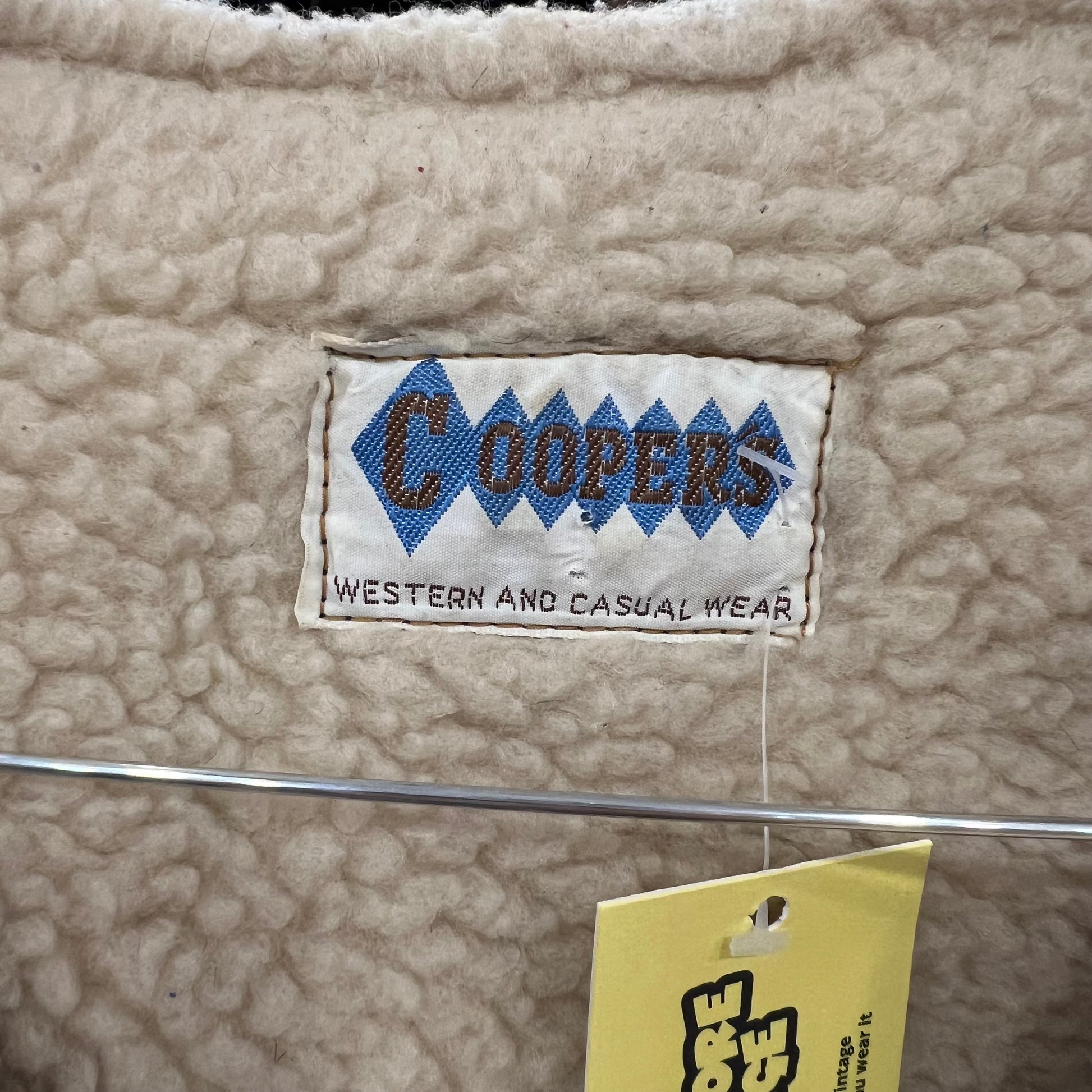Close-up of a label on a sheepskin fabric surface with 'Coopers' branding