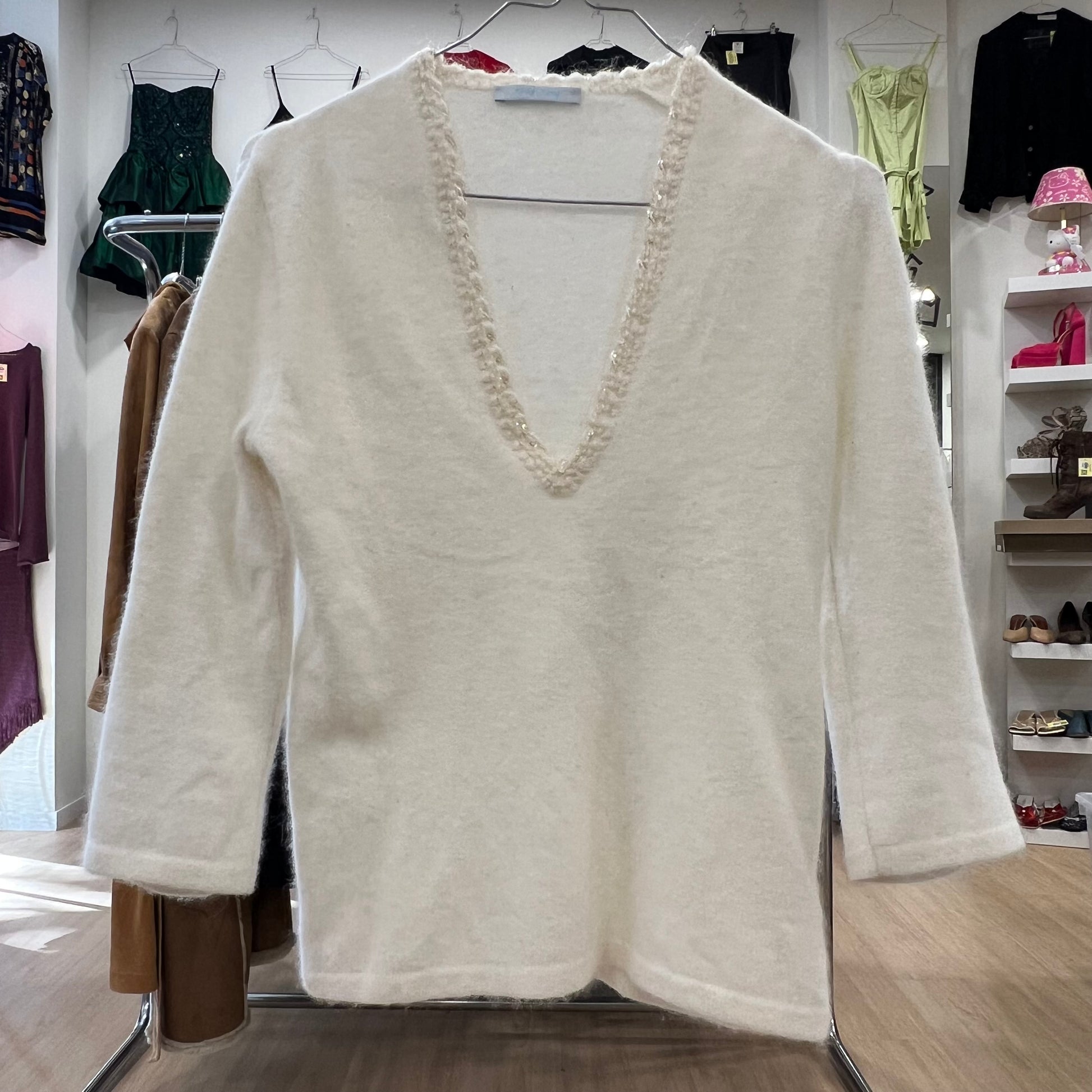 White sweater with lace detailing on a rack in a store setting