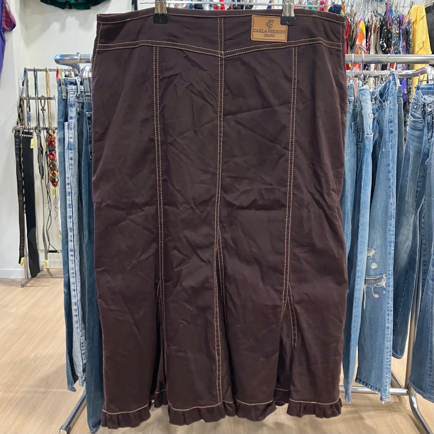 Brown skirt hanging on a rack with jeans in a store setting