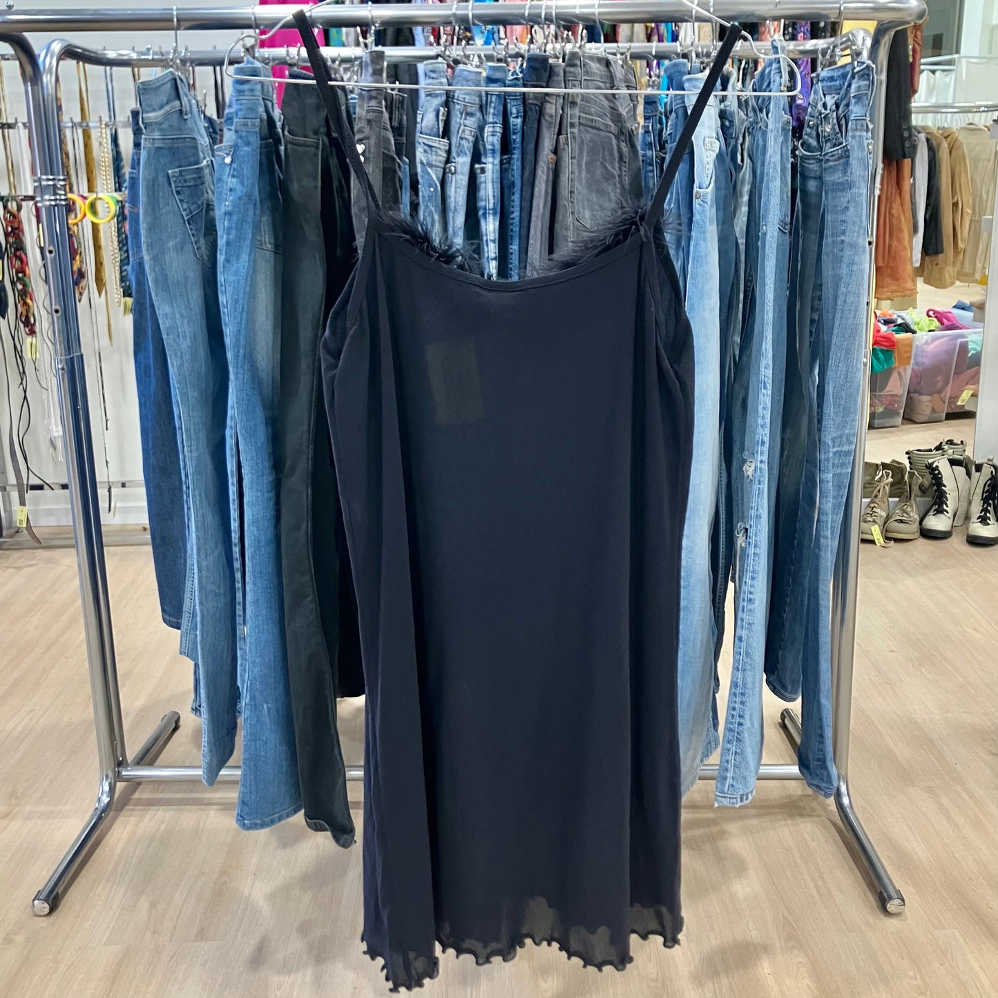 Black dress on a rack with jeans in a store setting