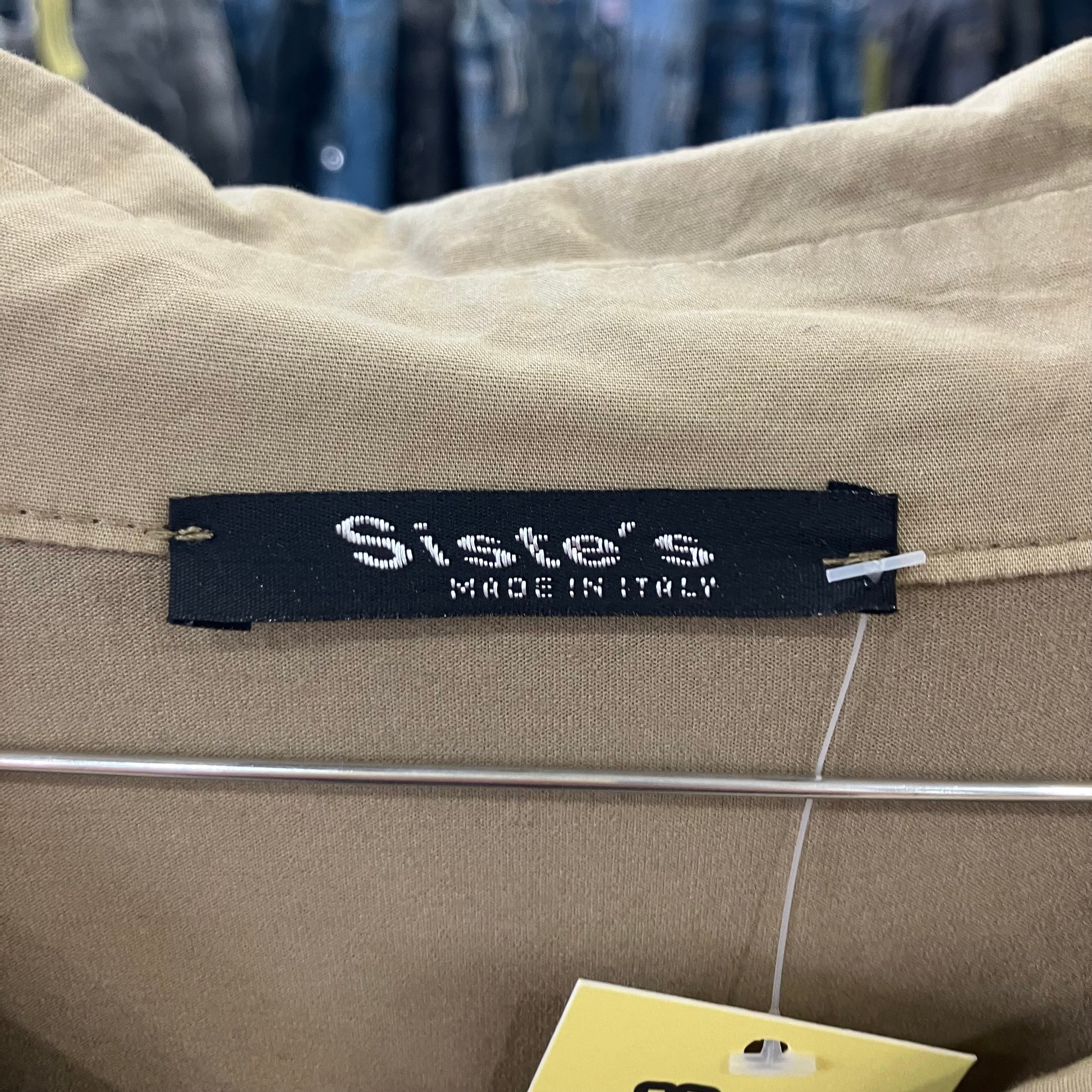 Label on beige fabric with 'Siste's Made in Italy' text, blurred background of clothing