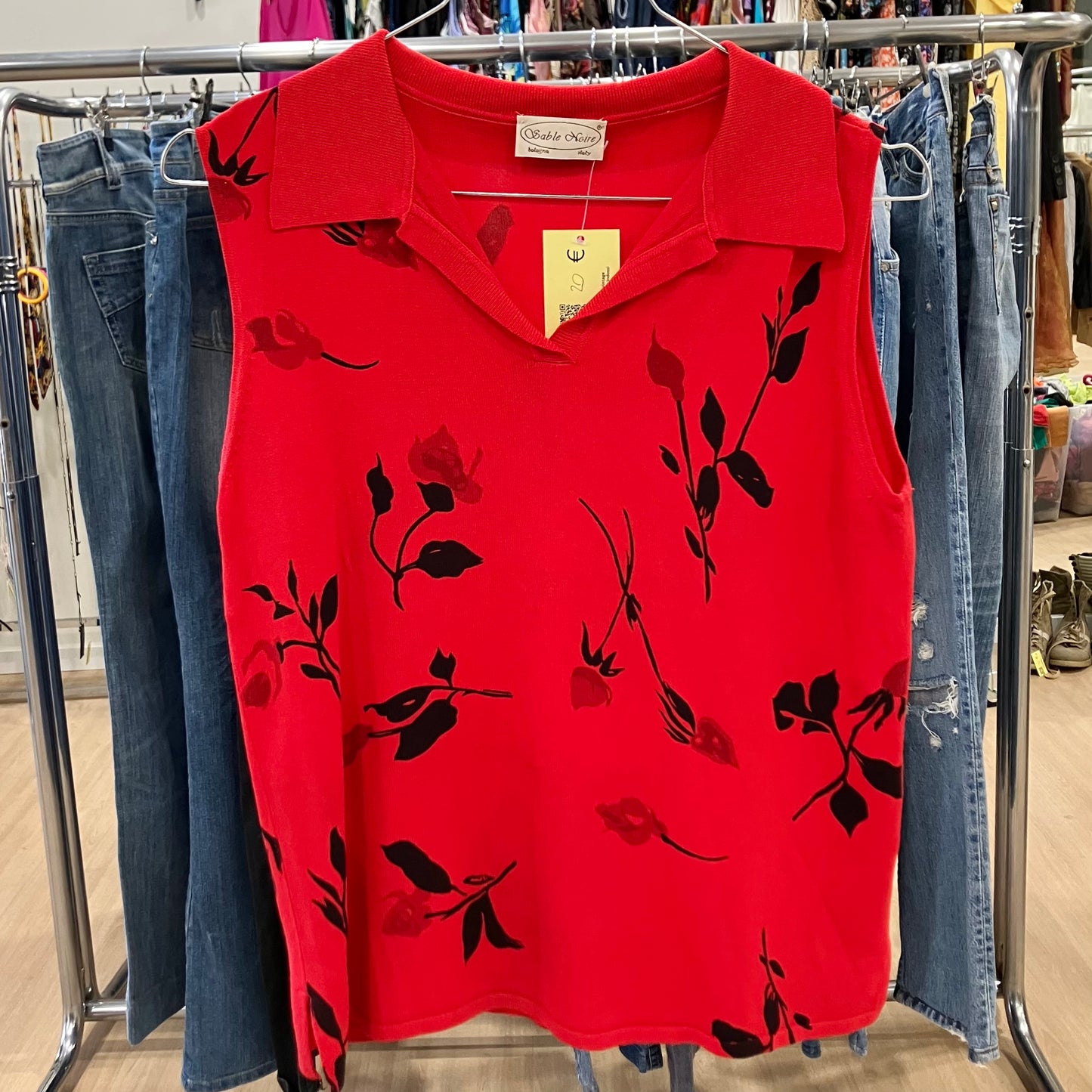 Red sleeveless top with black floral patterns on a clothing rack