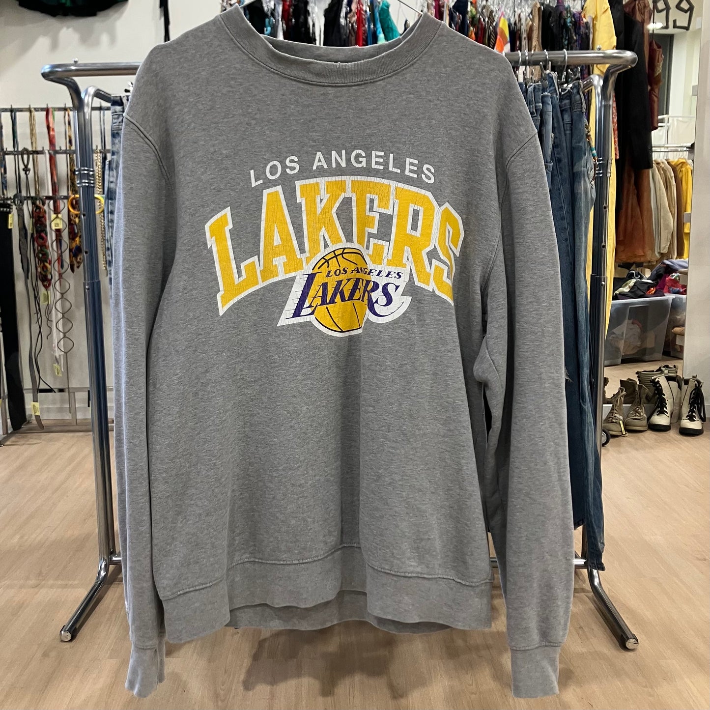 Gray sweatshirt with 'Los Angeles Lakers' logo on a rack in a store