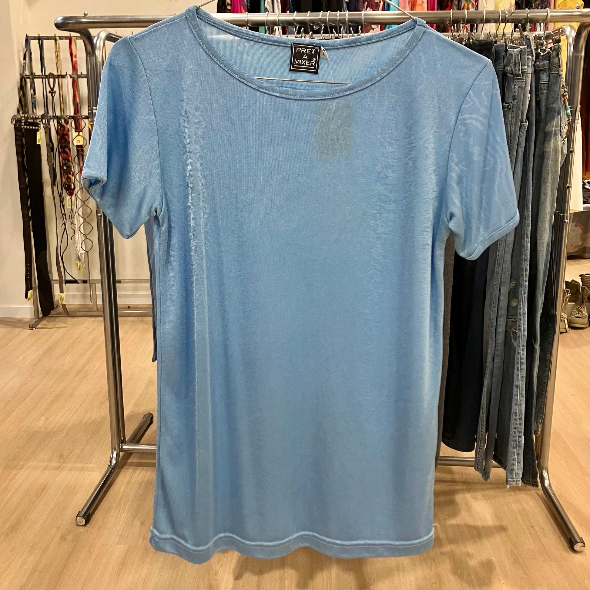 Light blue t-shirt on a hanger with a clothing rack in the background