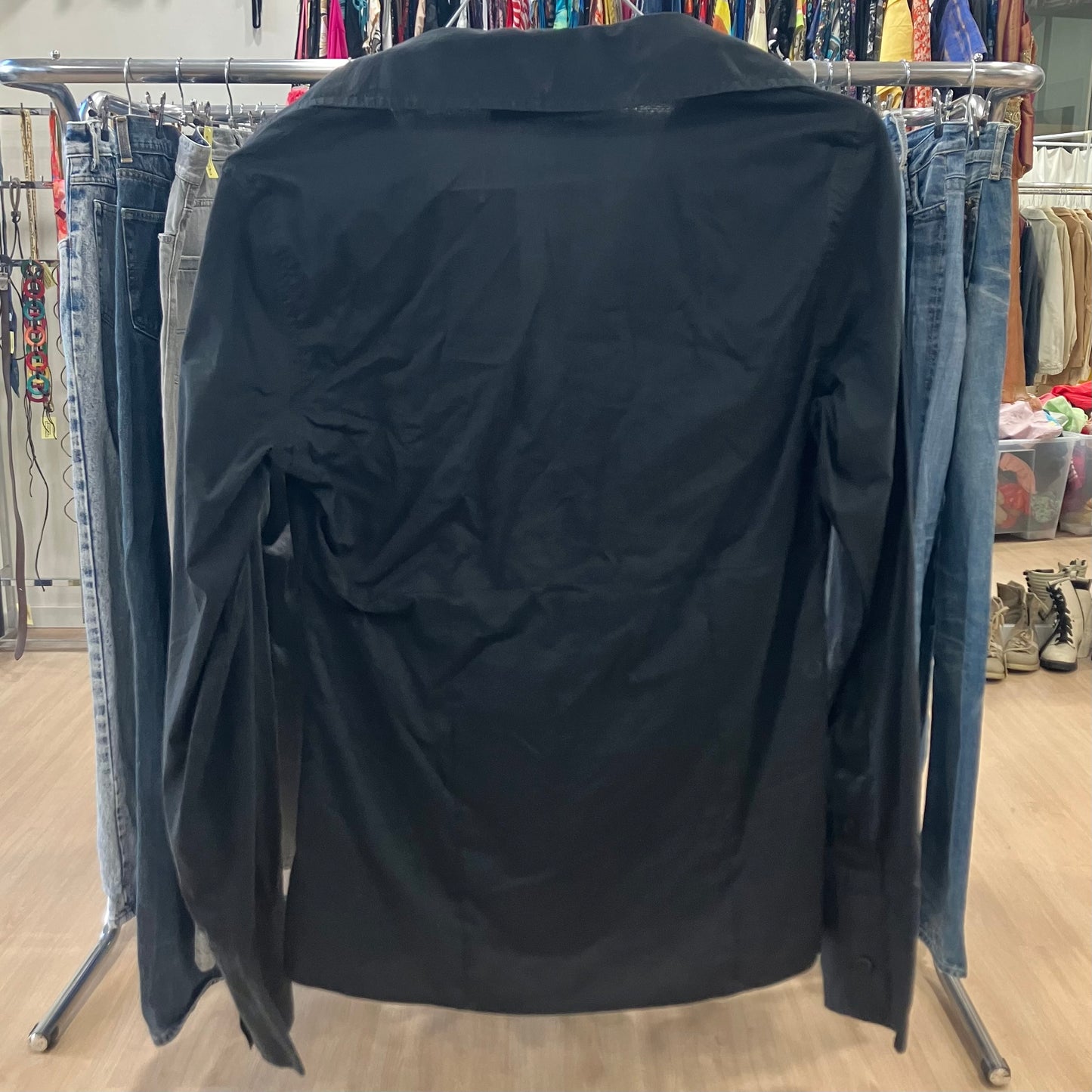 Black shirt on a clothing rack with jeans in a store setting