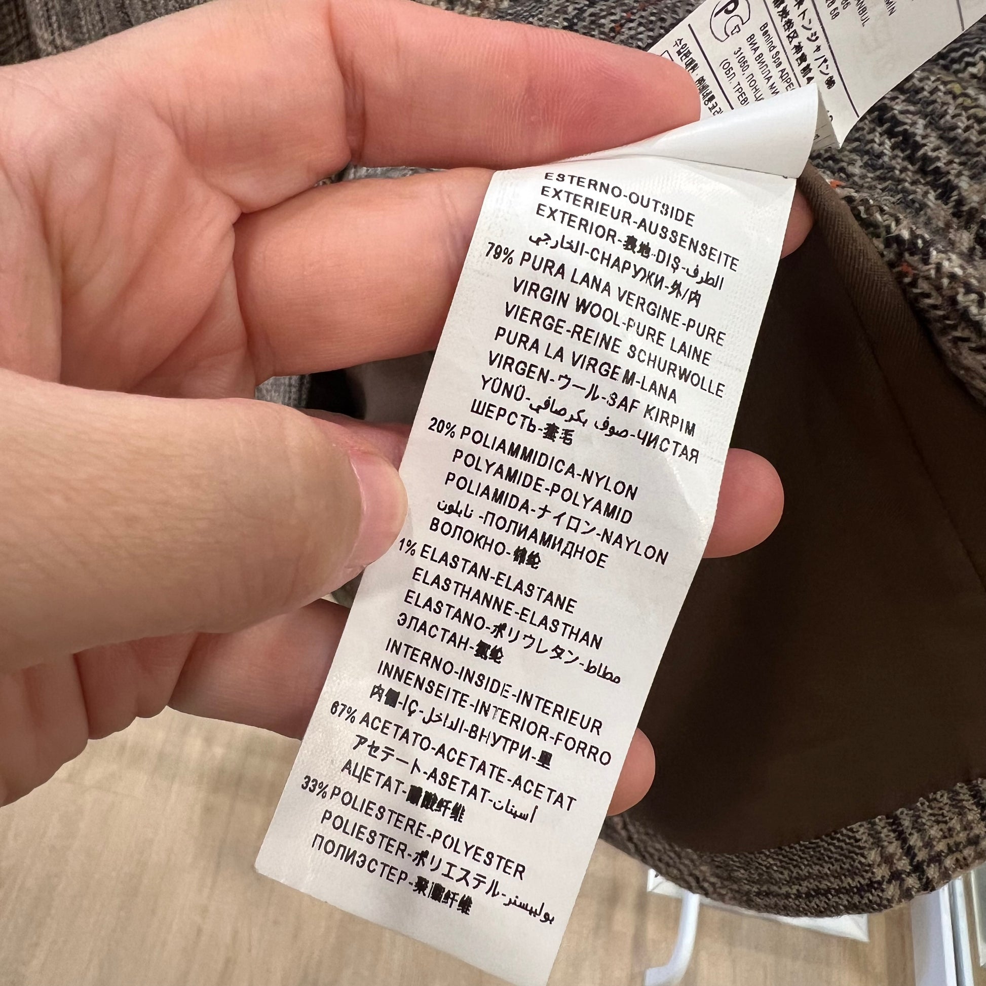 Hand holding a fabric label with text on a blurred background