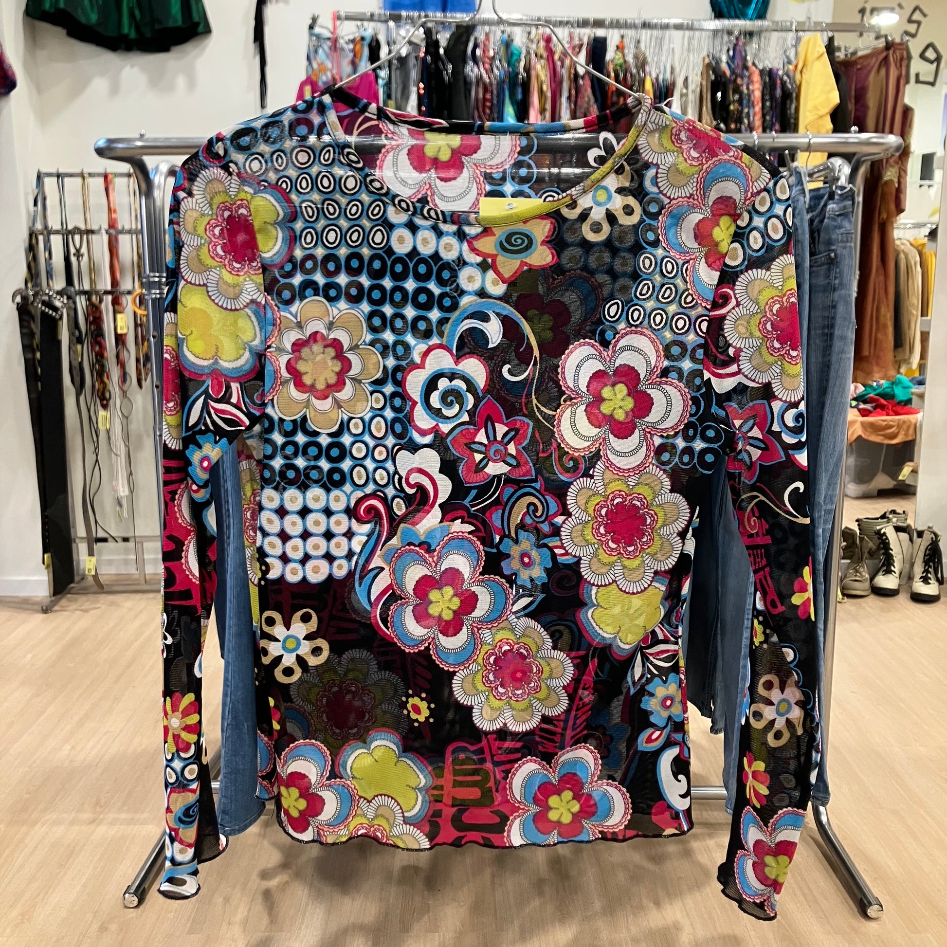 Colorful floral-patterned long-sleeve top on a rack in a store setting