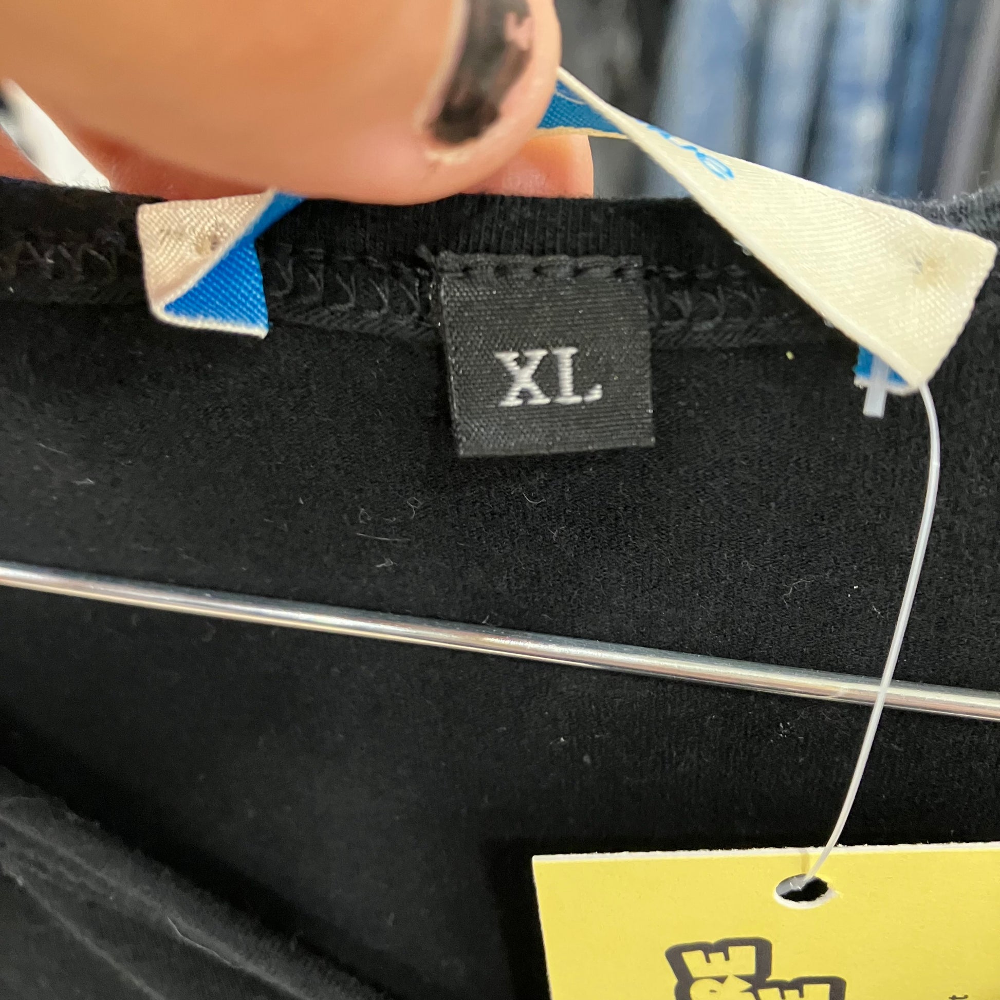 Black XL size tag on second hand shirt with hanger and yellow price label