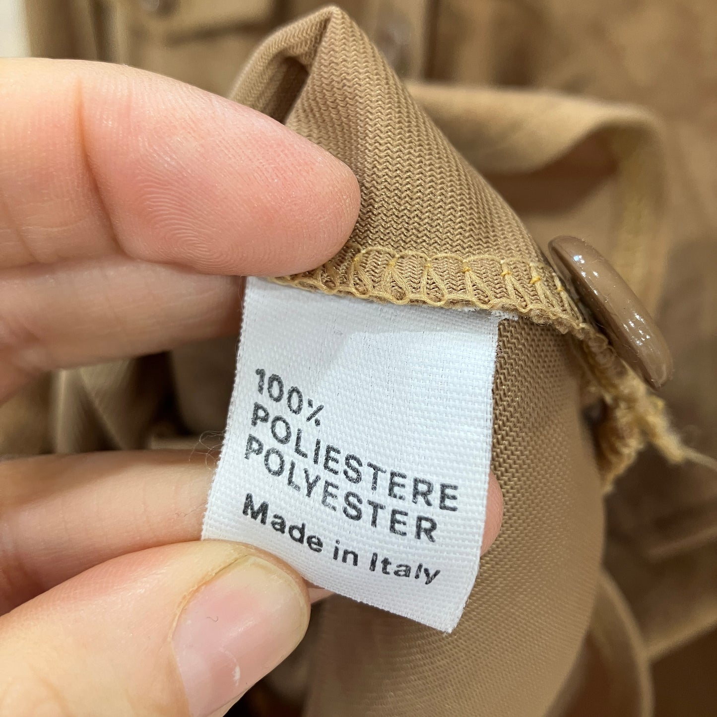 Close-up of a label on a brown garment indicating '100% Polyester, Made in Italy'
