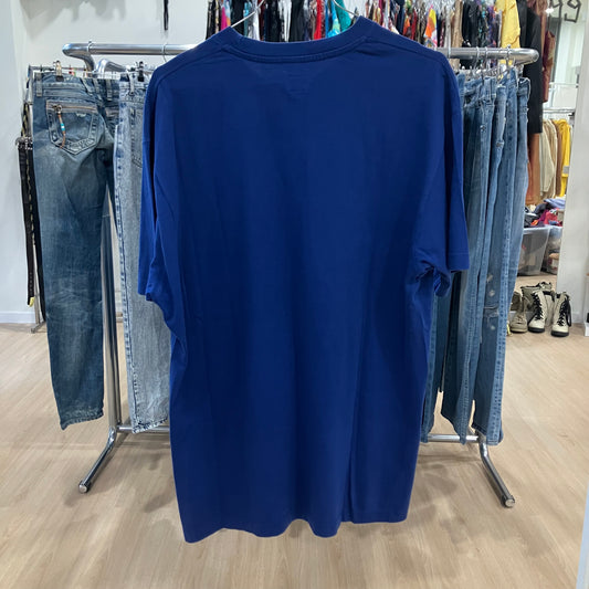 Blue t-shirt hanging on a rack in a store with jeans and other clothing in the background