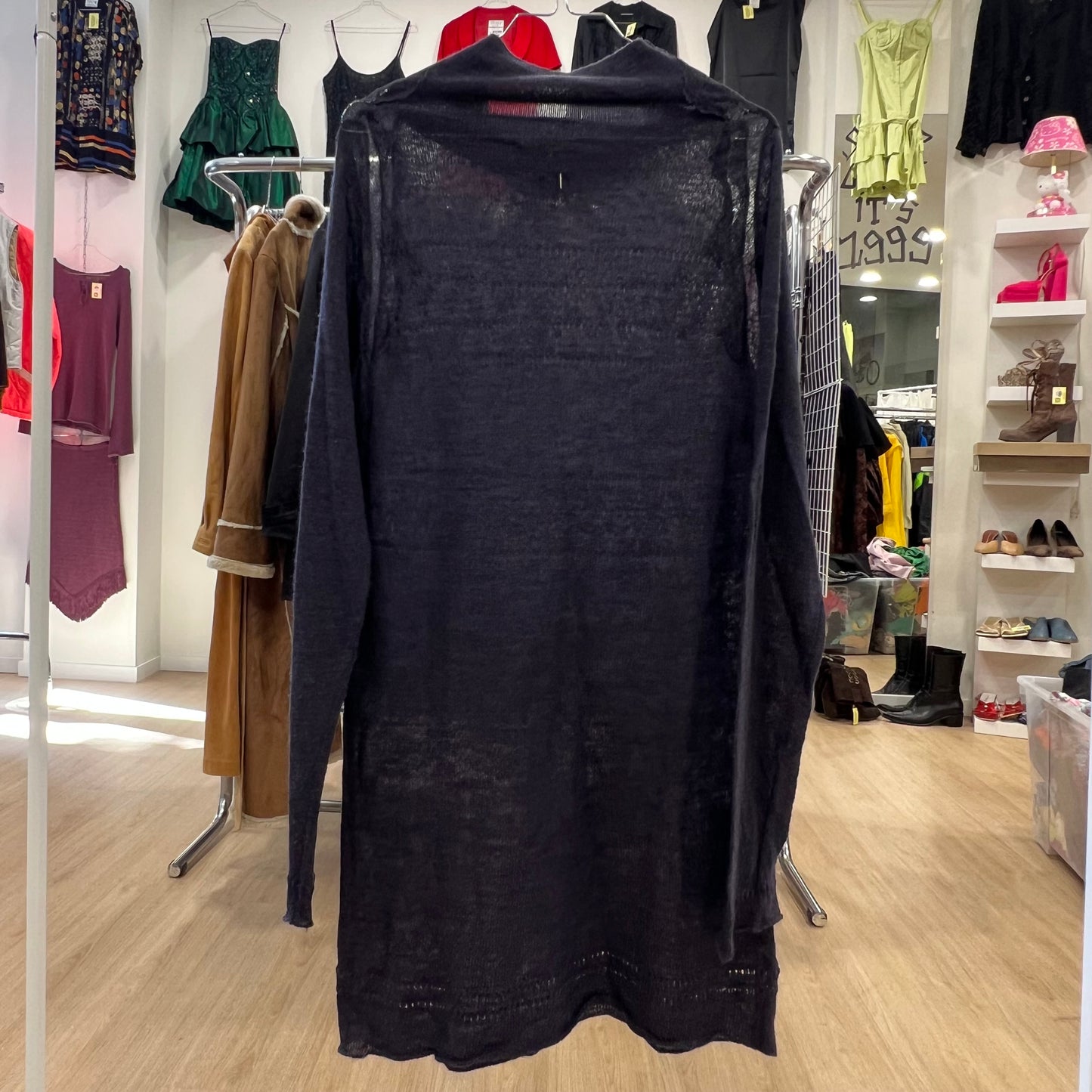 Black dress on a hanger in a clothing store with various garments in the background
