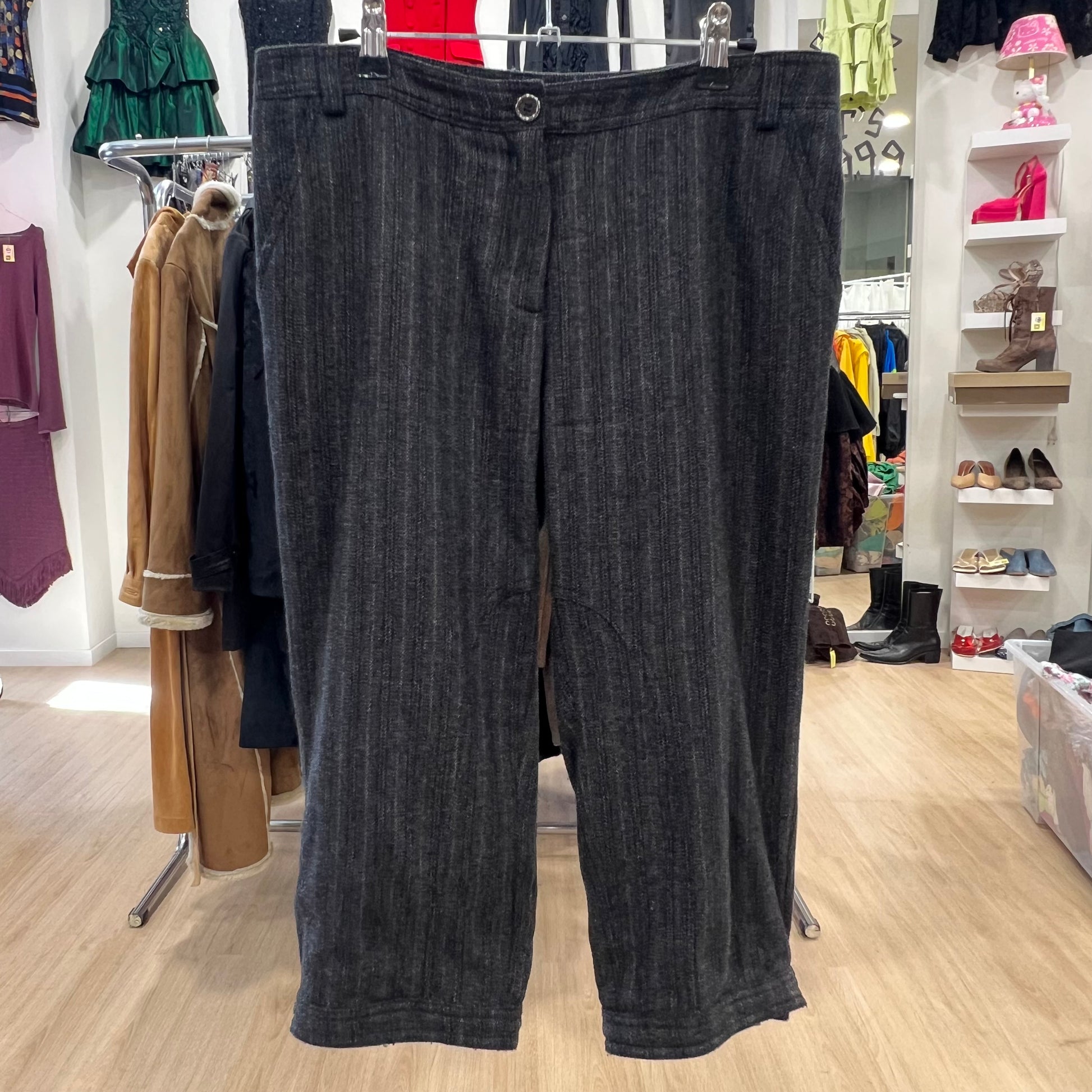 Dark gray pinstripe pants hanging in a store with clothing and shoes in the background