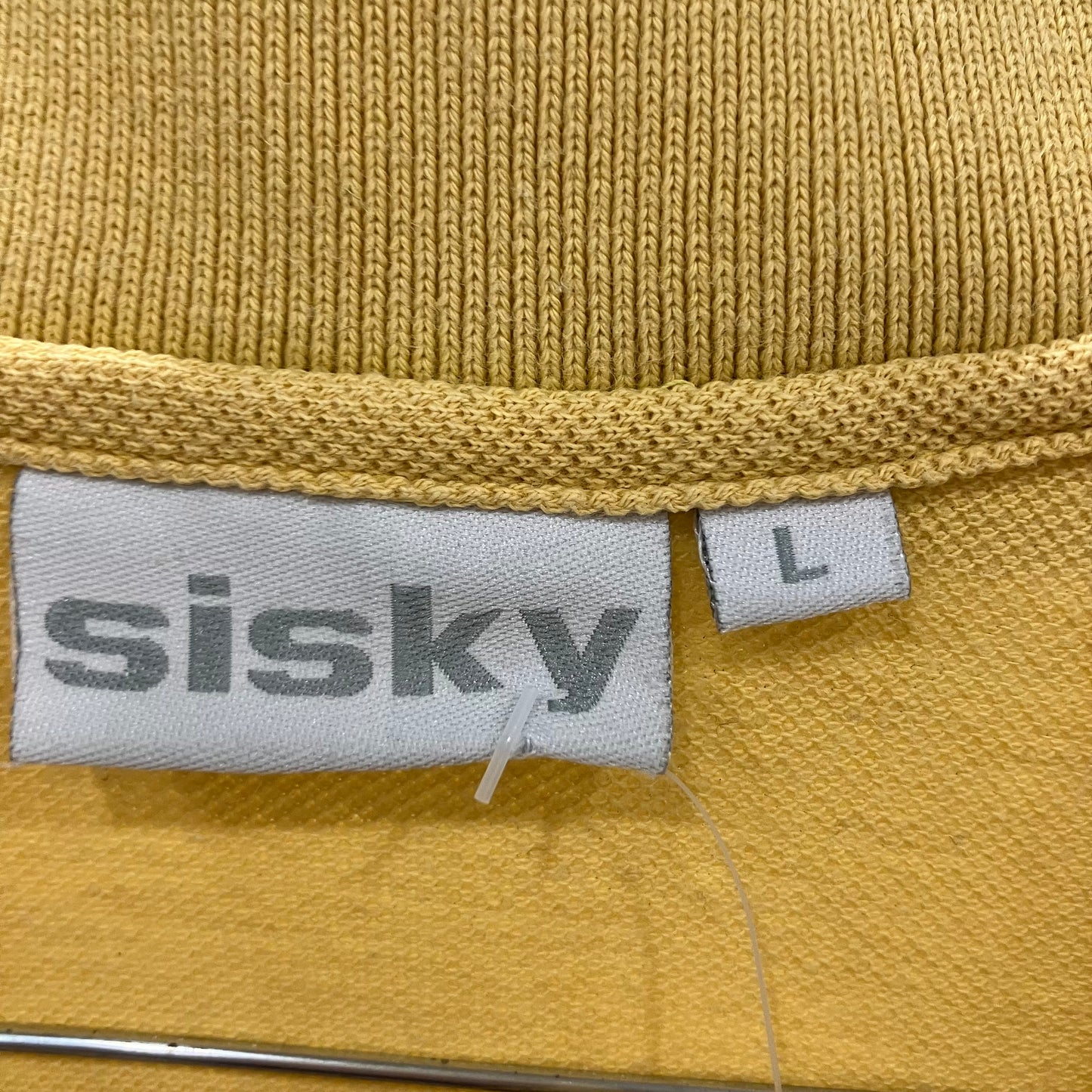 Close-up of a mustard yellow fabric with 'sisky' label and size 'L'