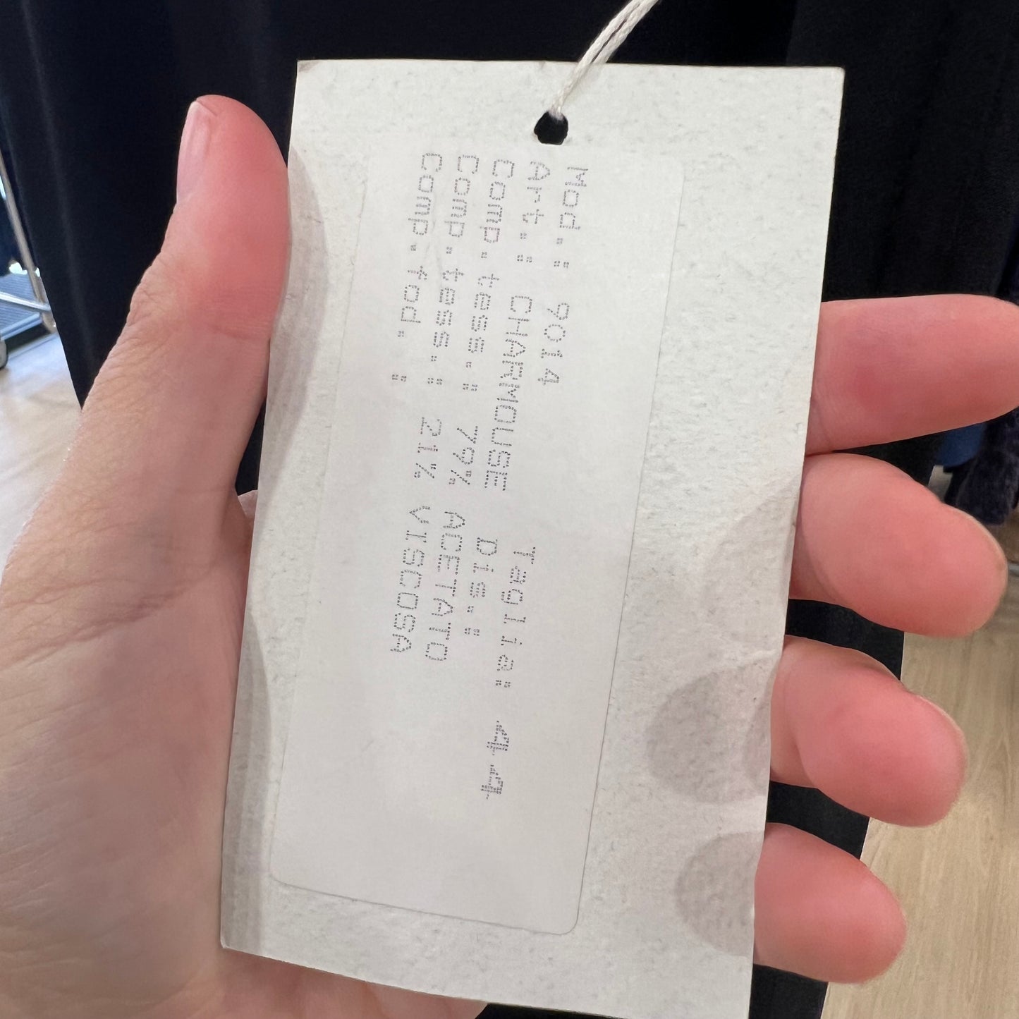 Hand holding a white tag with text
