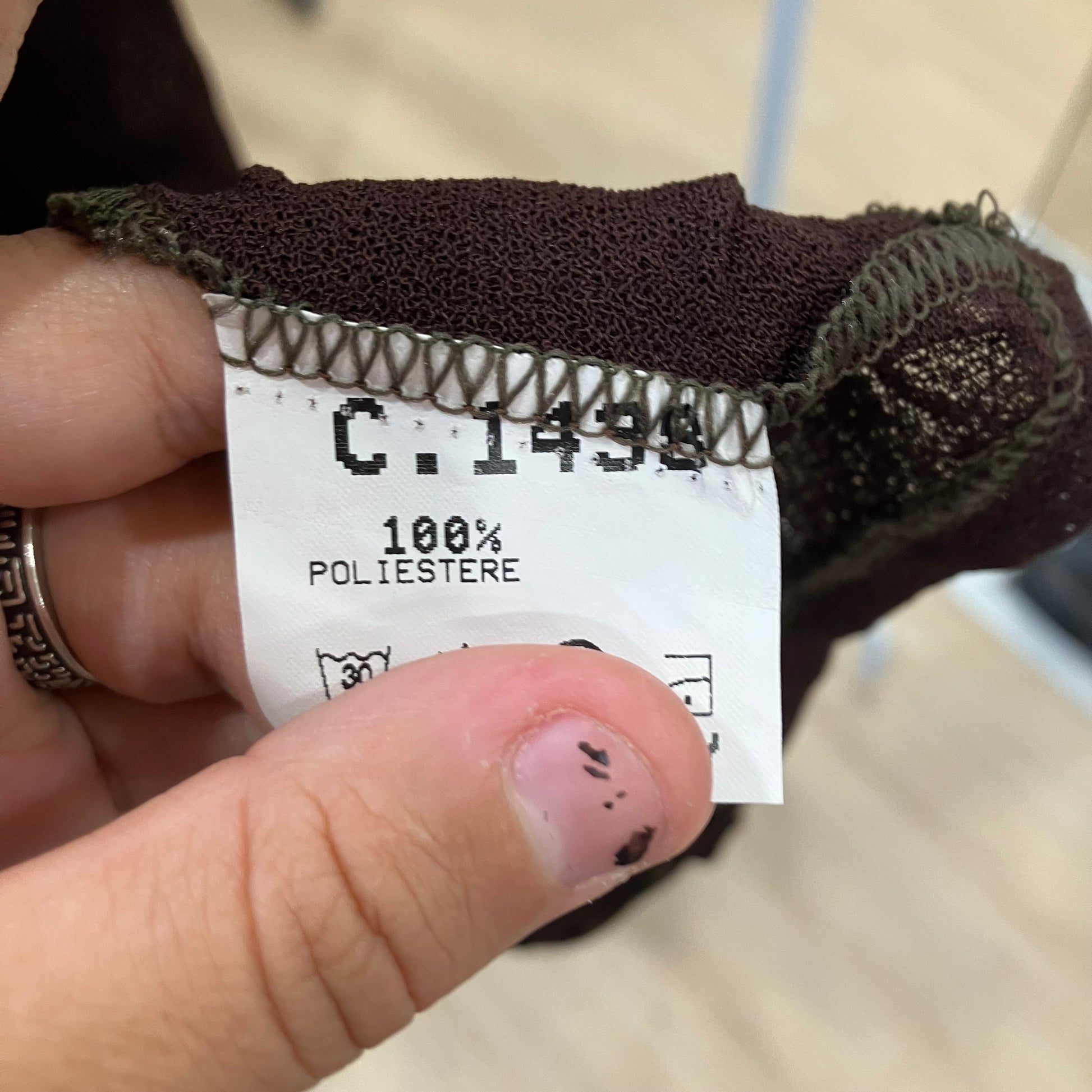 Close-up of a clothing tag with text and symbols on a blurred background