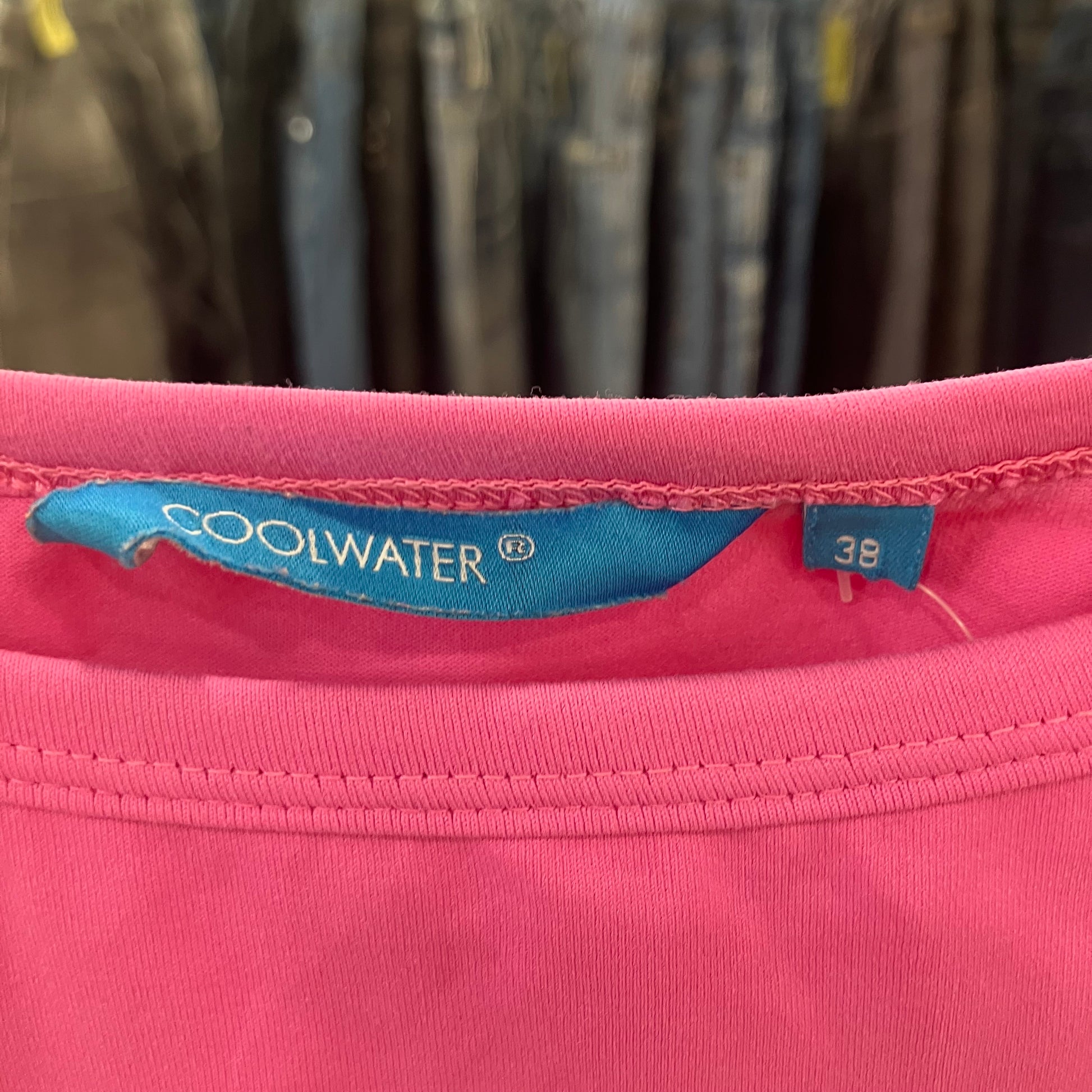 Pink garment with a Coolwater label on a blurred clothing background