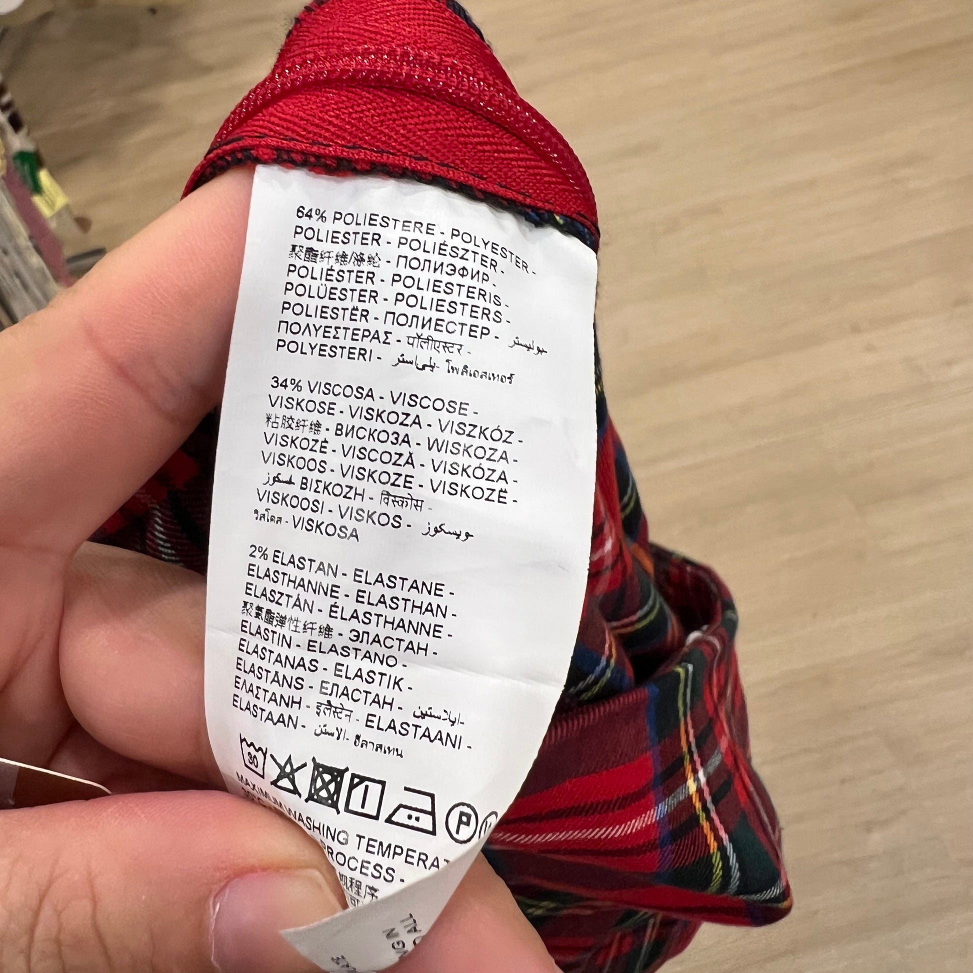 Close-up of a fabric label on a plaid garment with a blurred background