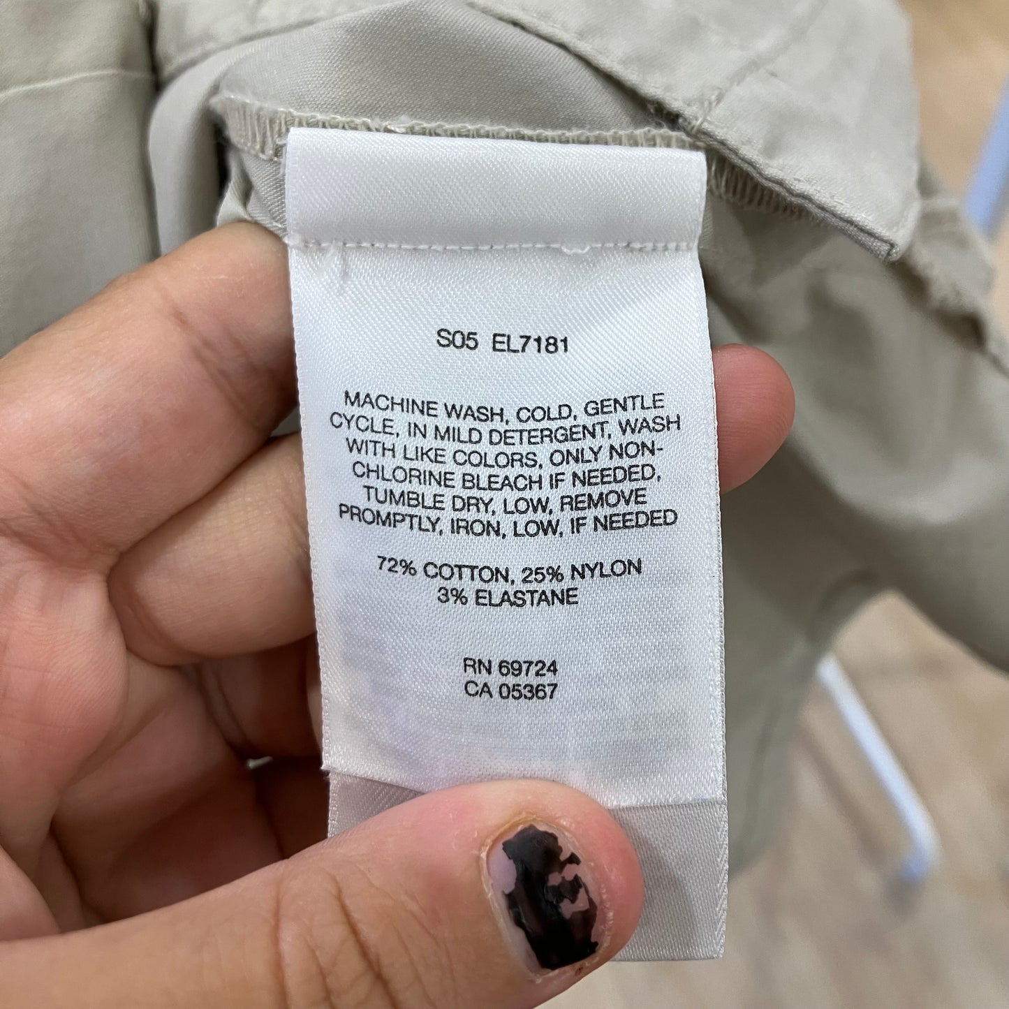 Clothing label with washing instructions and material composition held by a hand