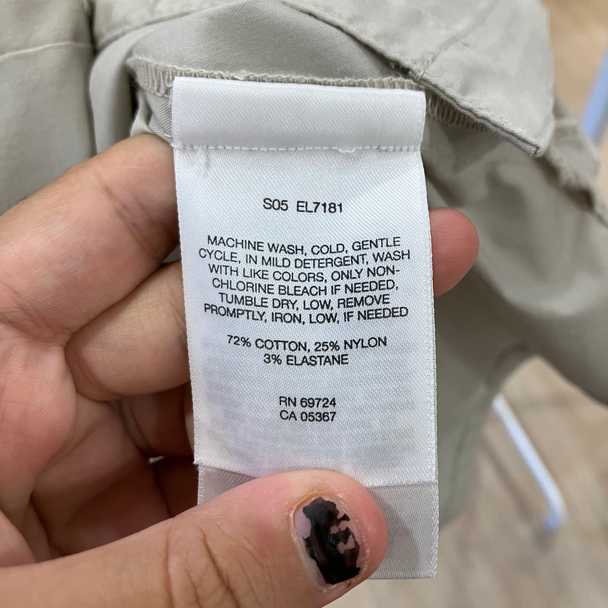 Clothing label with washing instructions and material composition held by a hand