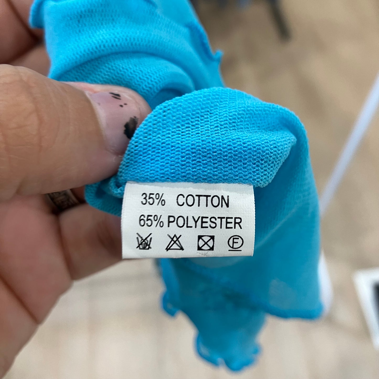 Blue fabric with a label showing 35% cotton and 65% polyester, held by a hand