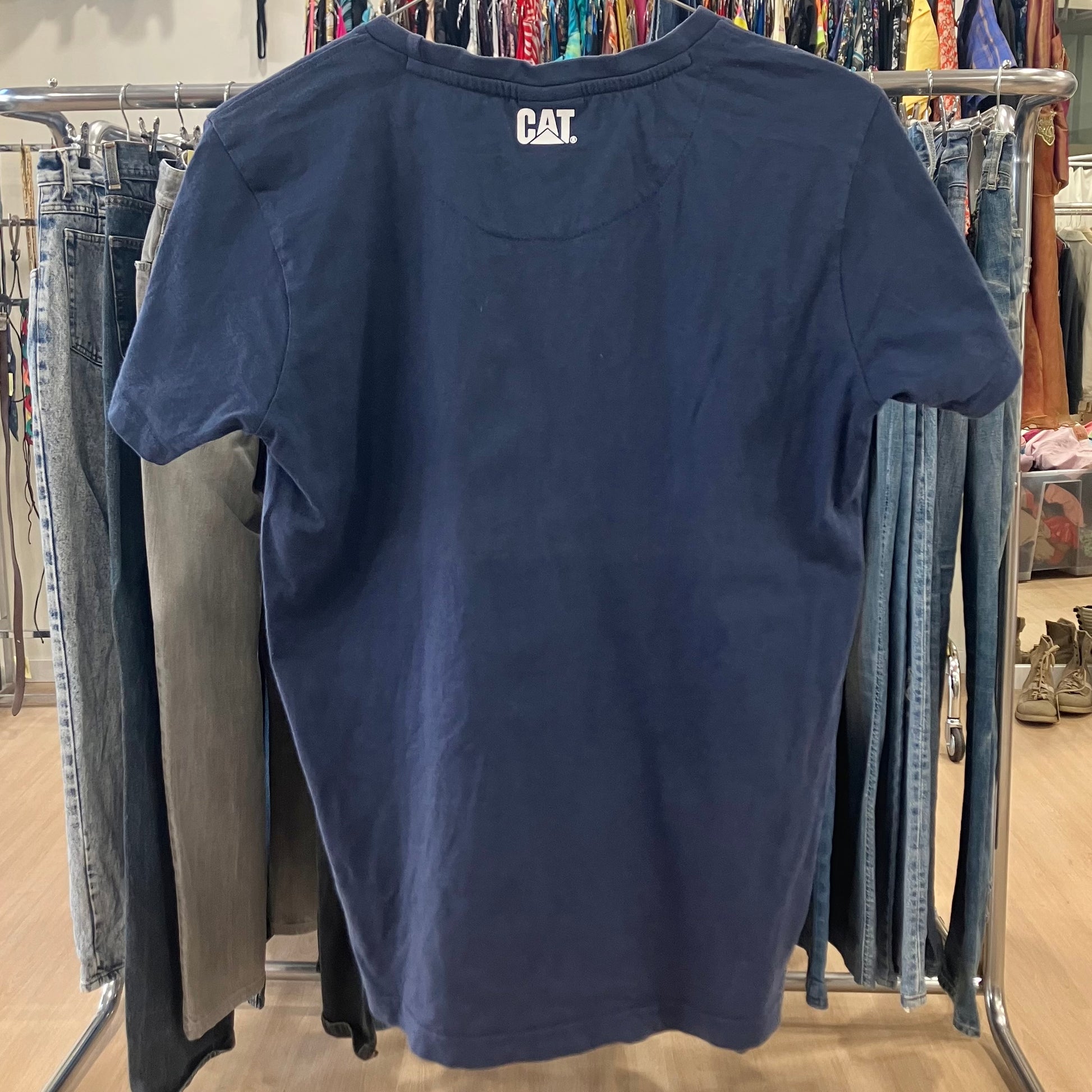 Navy blue t-shirt with 'CAT' logo on a clothing rack