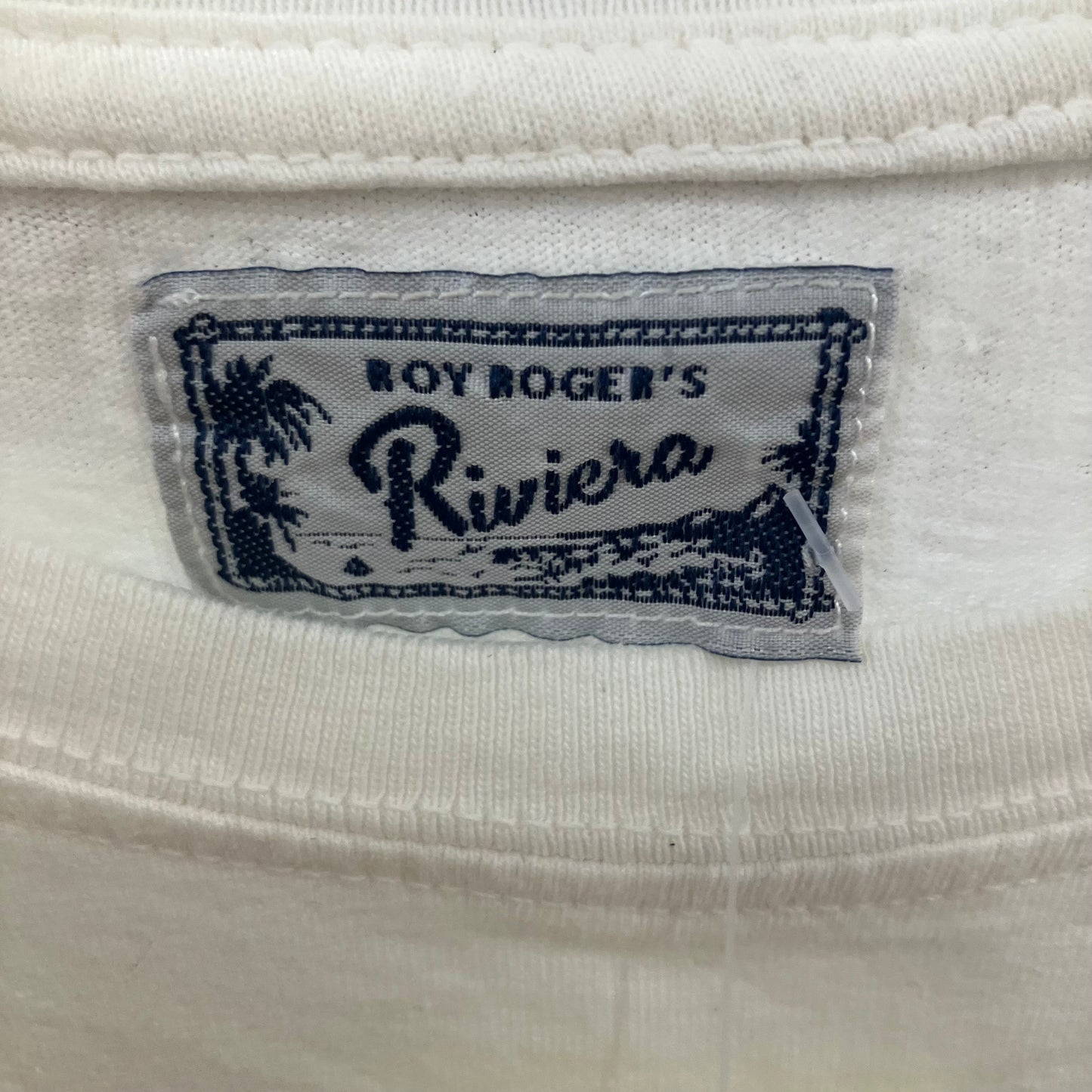 Close-up of a 'Boy Roger's Riviera' label on a white fabric background