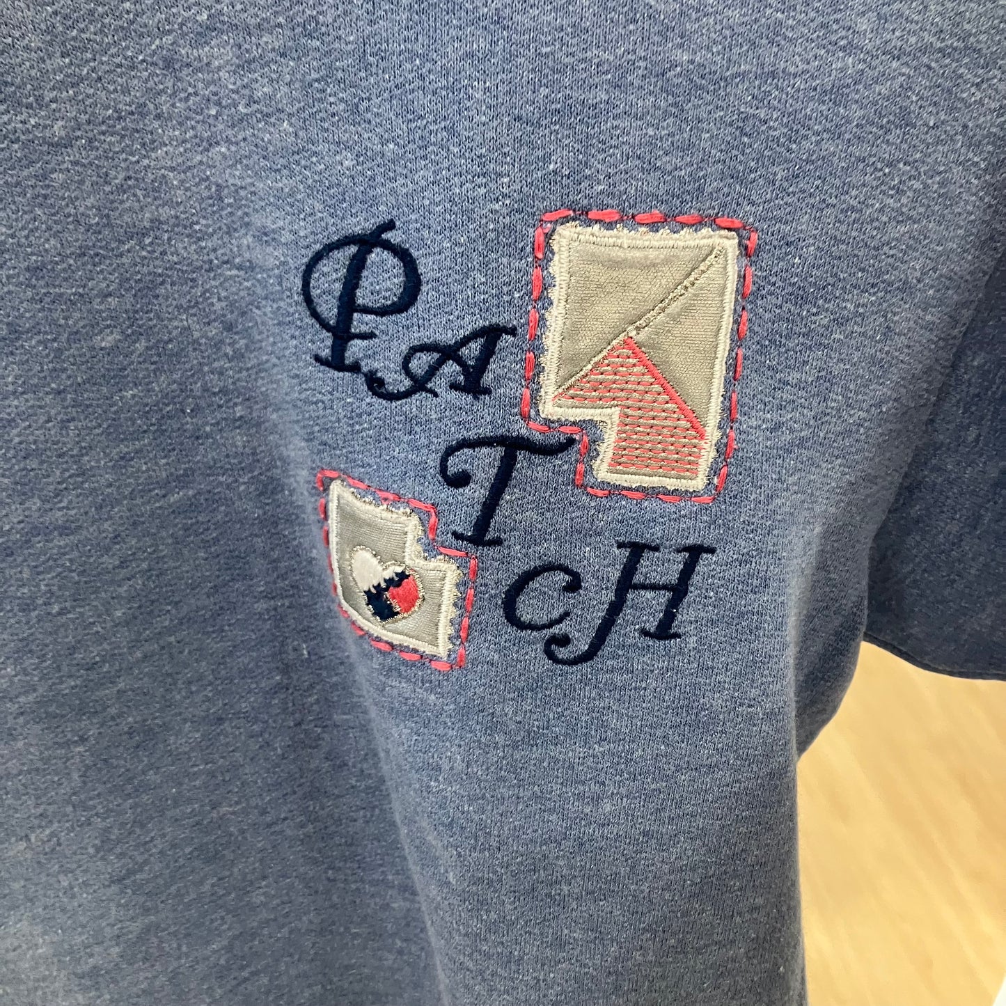 Gray sweatshirt with embroidered designs and text on a yellow background