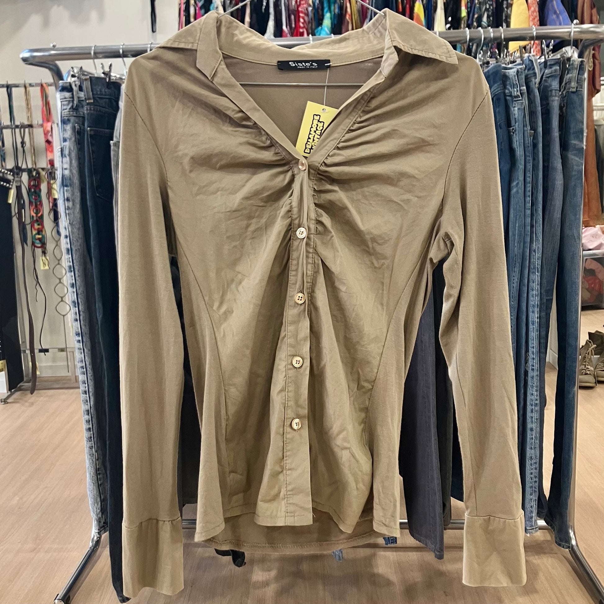 Beige button-up shirt with a tag on a rack in a store setting