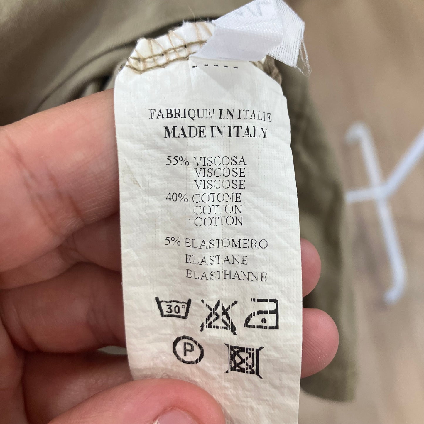 Clothing label with fabric composition and care instructions held by a hand