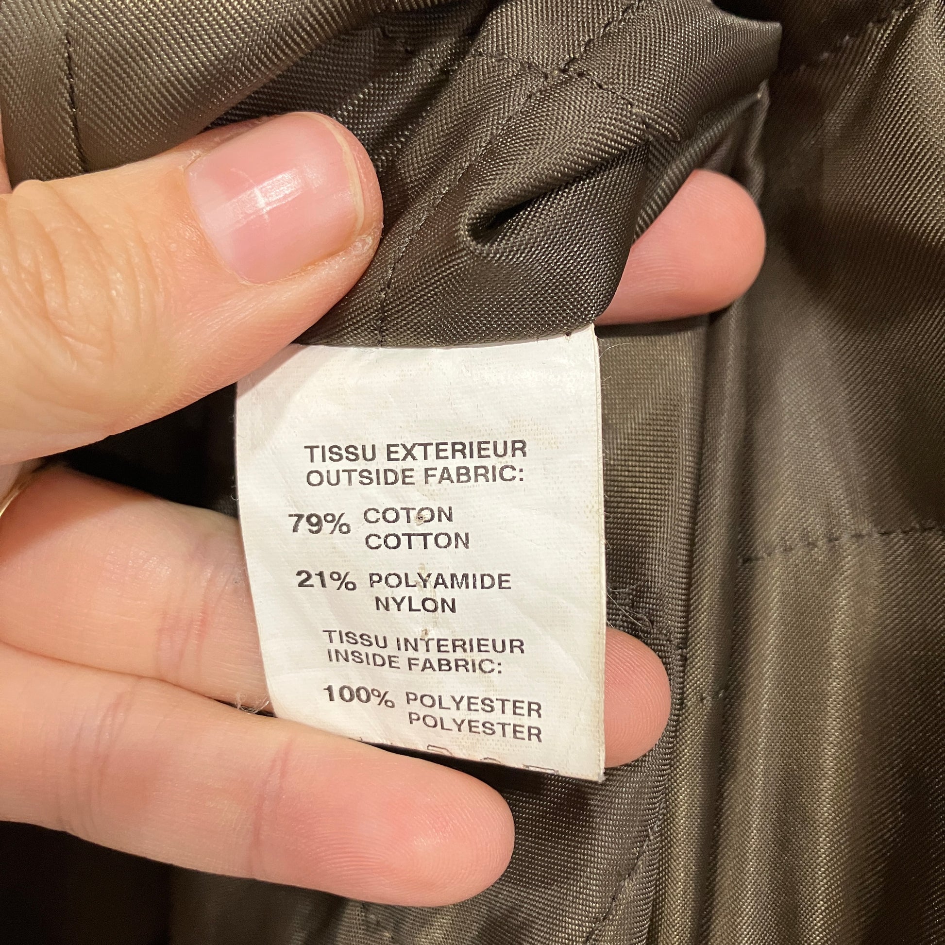 Fabric composition label on a jacket with a hand holding it