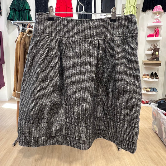 Black and white patterned skirt on a hanger in a store setting with shoes and clothing in the background