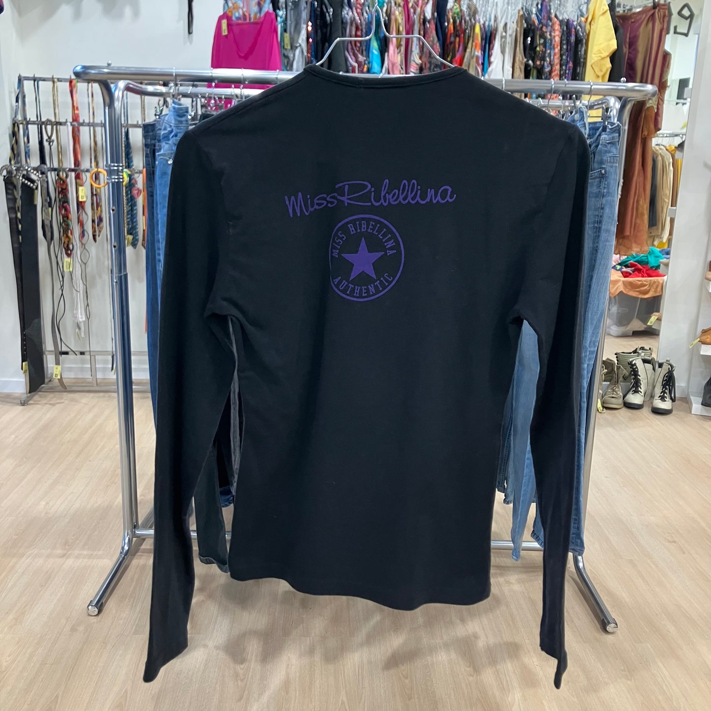 Black long-sleeve shirt with a logo on a mannequin in a store setting