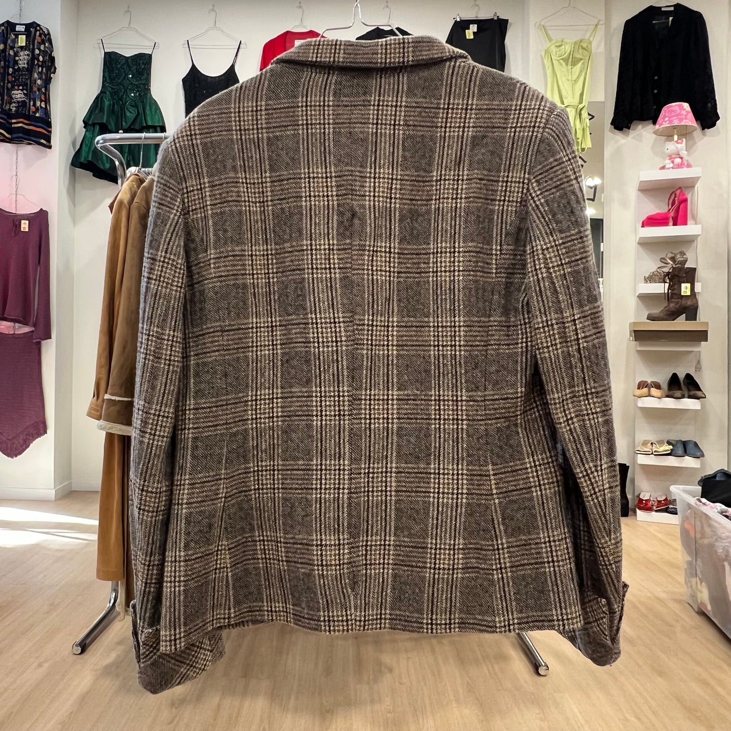 Plaid jacket on a mannequin in a clothing store with racks of clothes in the background