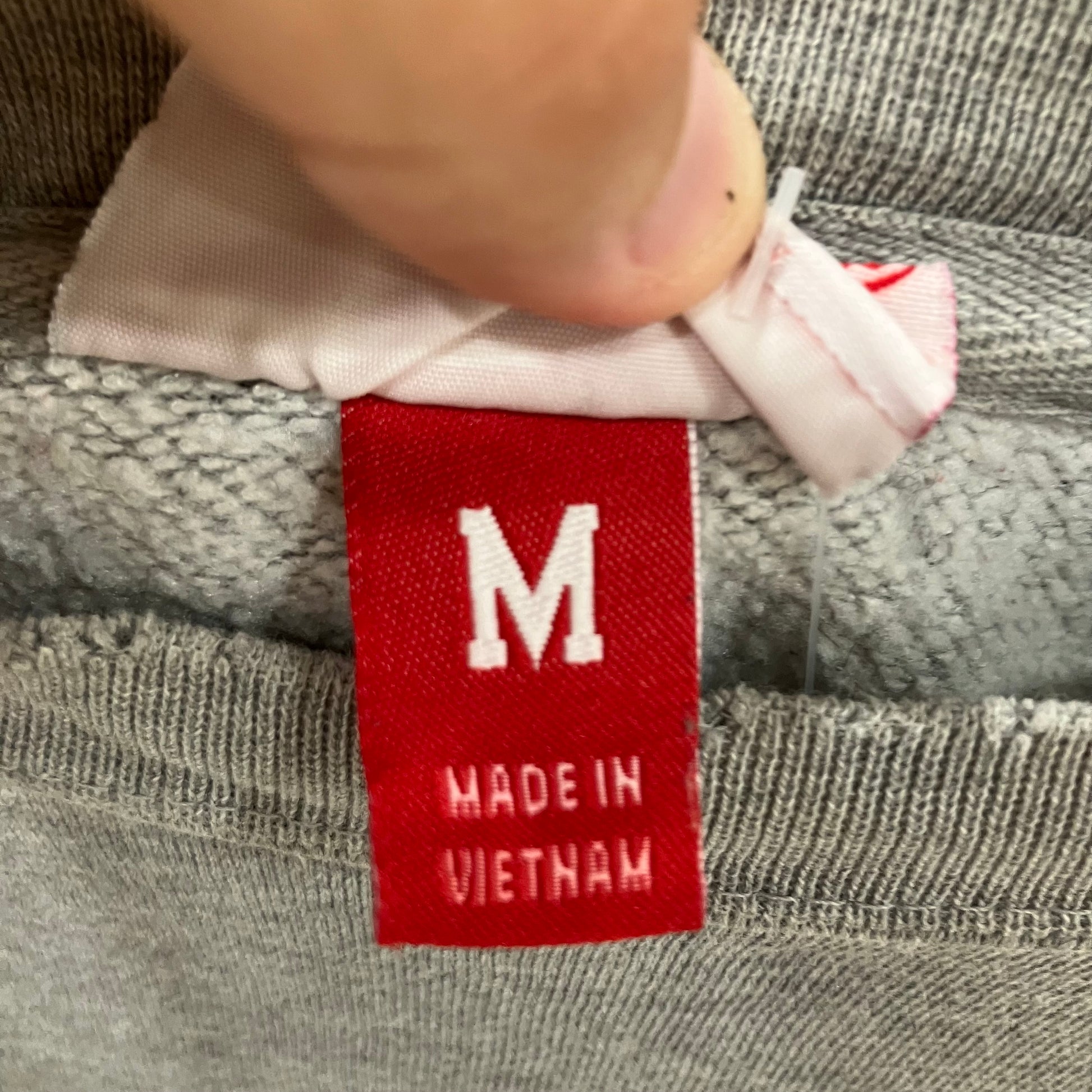 Red tag with 'M' and 'Made in Vietnam' on gray fabric
