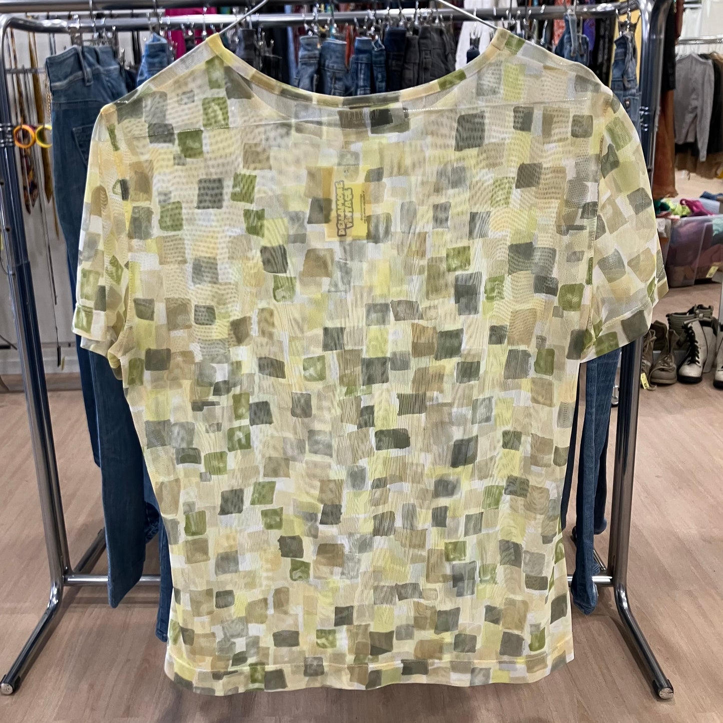 Green and yellow patterned shirt on a rack in a store setting